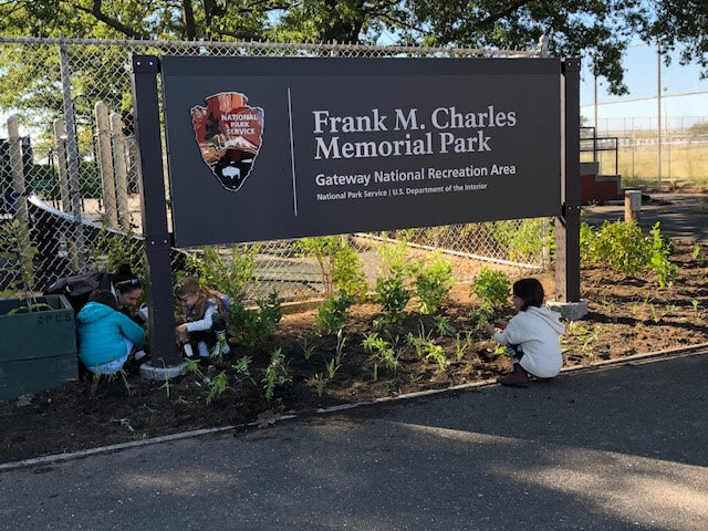 Volunteers plant around the entrance sign