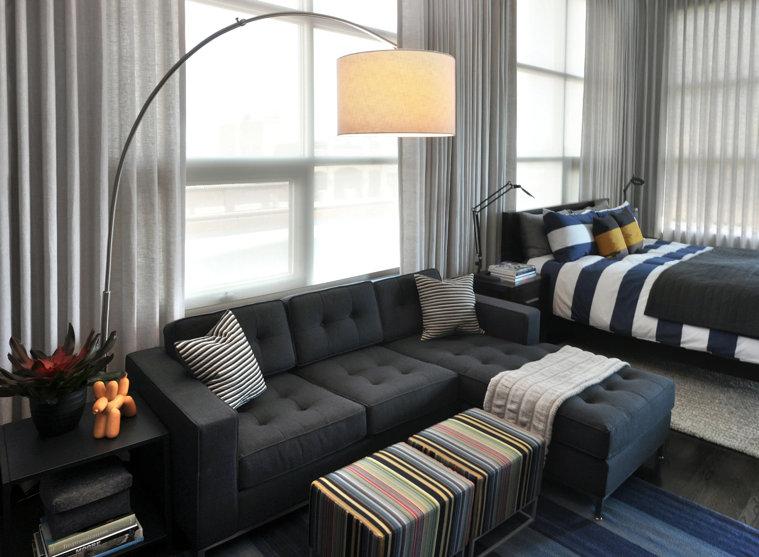 Creating this modern interpretation of a bachelor pad was pure fun! By first developing a neutral backdrop, we were able to imbue the space with an incredible amount of style through pops of color, custom designed furnishings, and an inspired art collection; including a floor-to-ceiling wall graphic installation by Chicago artist Connie Noyes. Through the aforementioned elements this space was fundamentally transformed from a boring industrial box to an environment built for inspiration and entertaining. What we did: When this particular client approached us, he had already had false-starts with two other interior designers. Through our client-driven process, we finalized space plans, selected thoughtful furnishings, designed custom pieces, and curated a full art collection of both local and nationally-recognized artists. 