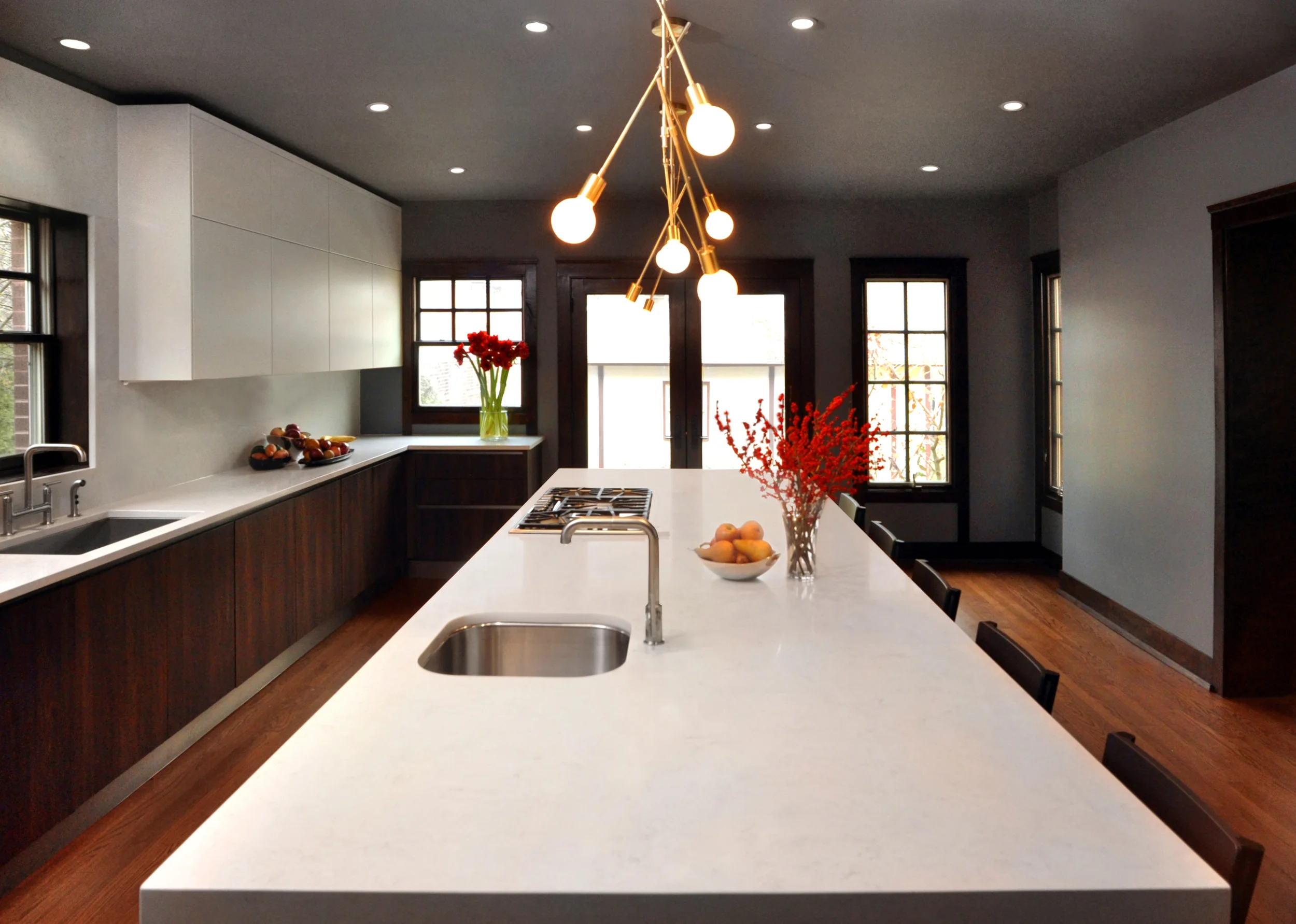 This generously proportioned craftsman-style home in Oak Park boast 425 square feet of kitchen space. In its original renovation, by the previous owners, the kitchen was chopped up and styled in a way that was out of touch with the clean-line architecture of the home. NMI designed a spacious modern kitchen filled with material elements reminiscent of the mid-century era in which the home was built. Light gray lacquer, walnut, brushed brass, and Caesar stone were all thrown into the mix to give the kitchen a timeless quality. In addition, the creation of multiple task-oriented areas makes this kitchen multi-dynamic and hyper-functional. What we did: Working hand in hand with the clients to understand their functional needs and desires, NMI assisted the clients with a complete architectural redesign of the kitchen that included the selection of materials and appliances that bridge the gap between aesthetics and functionality. The redesign also included the implementation of a multi-level lighting plan, relocation of plumbing lines, gas lines, and the exhaust for the stove.