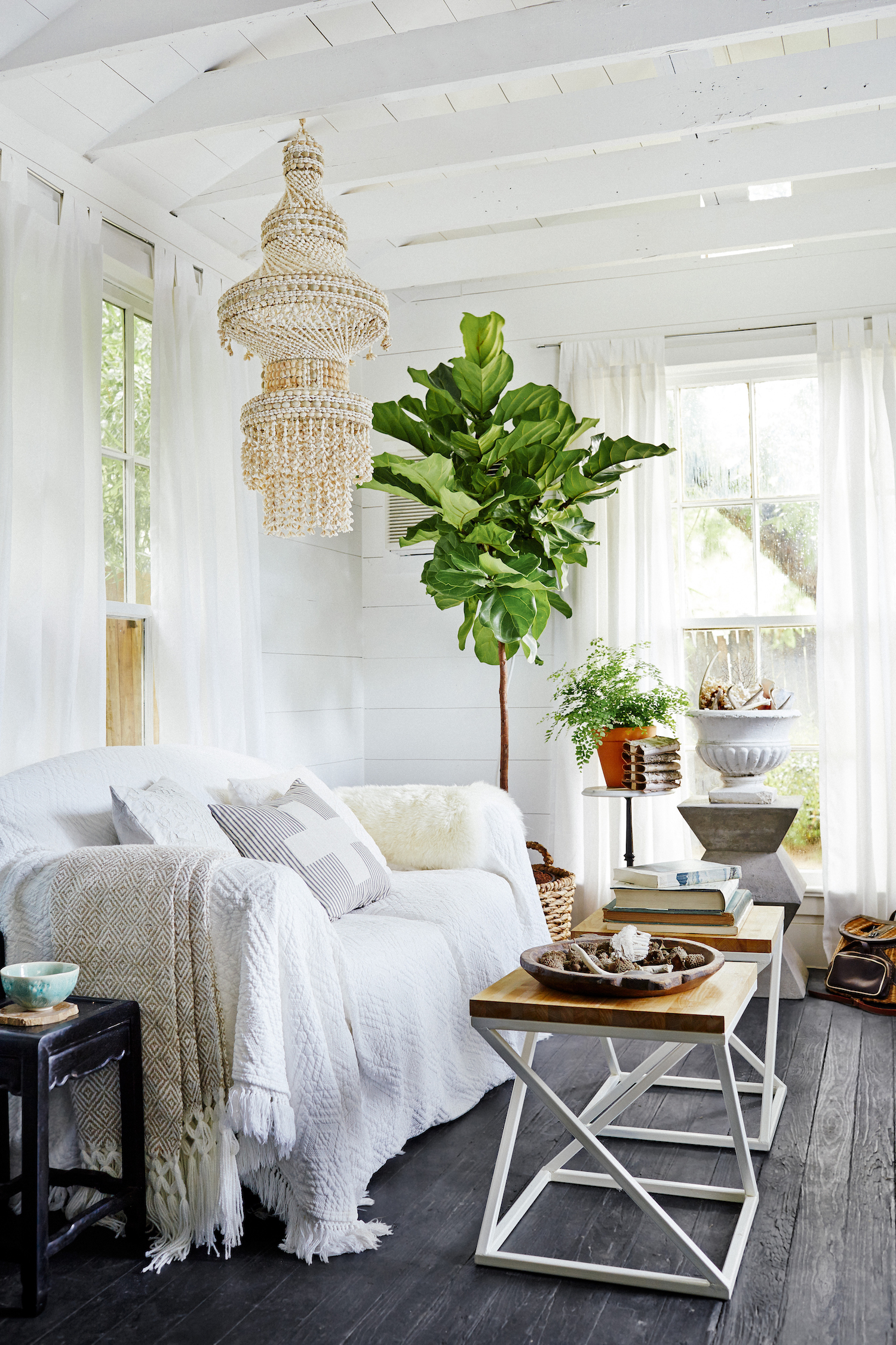 La casita. Photography: Cody Ulrich, p107.jpg – “A stunning chandelier that Morse made from shells hangs over the main living area of her shed. The sofa serves as her bed when she stays here. Handsome wood flooring is mostly original, painted black. Above the beams, a former air vent now serves as a small window.”