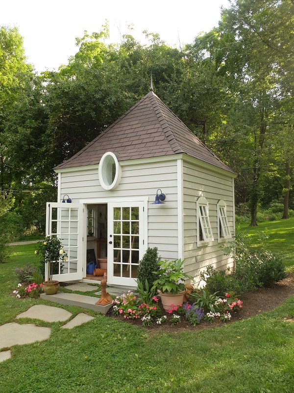 Ken Smith designed a more steeply pitched roof and included a small oval window and French doors. Two custom-made barn lights in deep cobalt blue complete the facade.