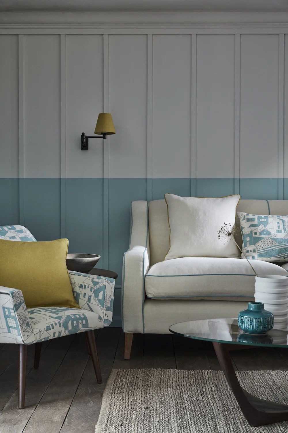 CHAIR: By the Sea Teal, Charcoal SEA-20-38 £52/mtr, CUSHION (on chair): Self piped and zipped Plain Linen Saffron PLAIN-52 £48/mtr, CHEDWORTH SOFA: Plain Linen Cream PLAIN-3 £48/mtr piped in Plain Linen Teal PLAIN-20 £48/mtr, CUSHION (left): Plain Linen Cream PLAIN-3 £48/mtr piped in Plain Linen Saffron PLAIN-52 £48/mtr, CUSHION (right): Rectangular self piped and zipped By the Sea Teal, Charcoal SEA-20-38 £52/mtr, LAMPSHADE: Plain Linen Saffron PLAIN-52 £48/mtr, LIGHT FITTING: Hanson Wall light in Matt Black by Jim Lawrence £87.20, RUG: Handmade Looped by Scumble Goosie £49 each, PAINT: Main wall Linen Wash 33 and Brighton 203 by Little Greene Paint Company £42 per 2.5 ltr.