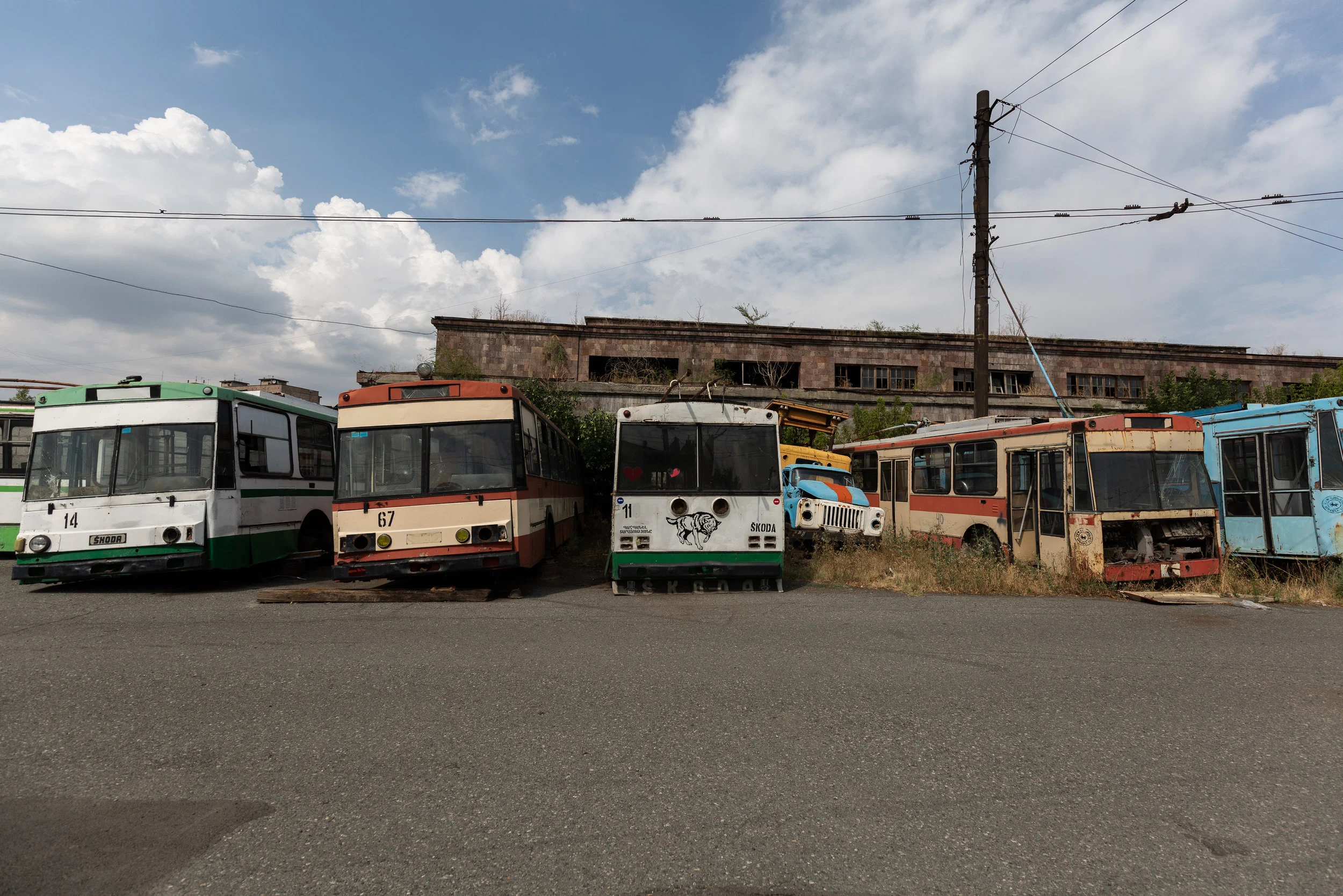 At the end of each day the trolleybuses are brought to this location to be stored and serviced. The massive empty lot is like a trolleybus graveyard with many left behind to rust or be stripped for parts. Some of the vehicles date back to the 1970s. Models range from the retired Czech Škoda 9Trs and Soviet ZiU-682s to Czech Škoda 14Tr, Russian LiAZ-5280, and French (Renault) Berliet ER100 from Lyon. 