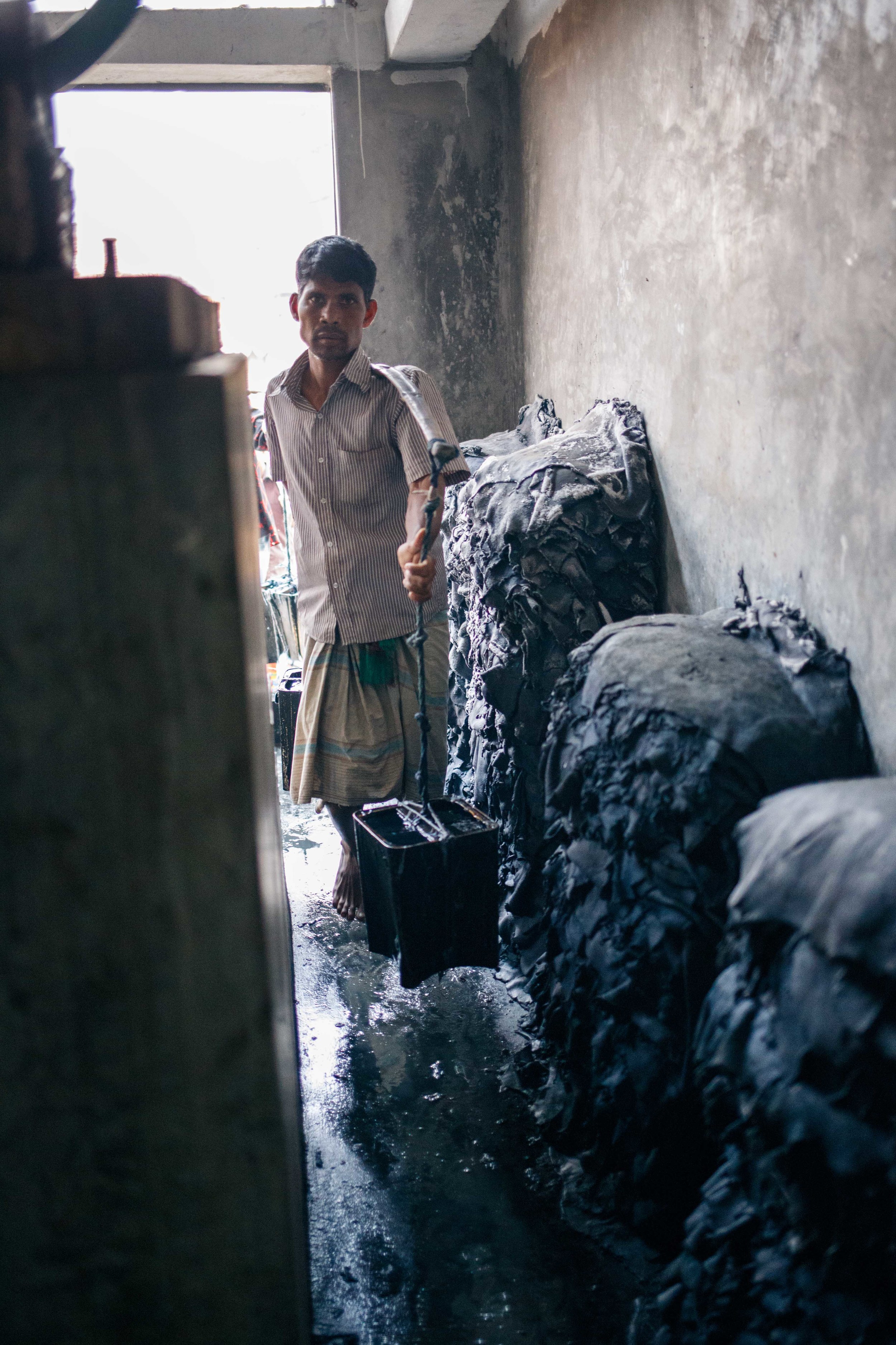  A man carries buckets of acid to dump into the bleaching pits. 