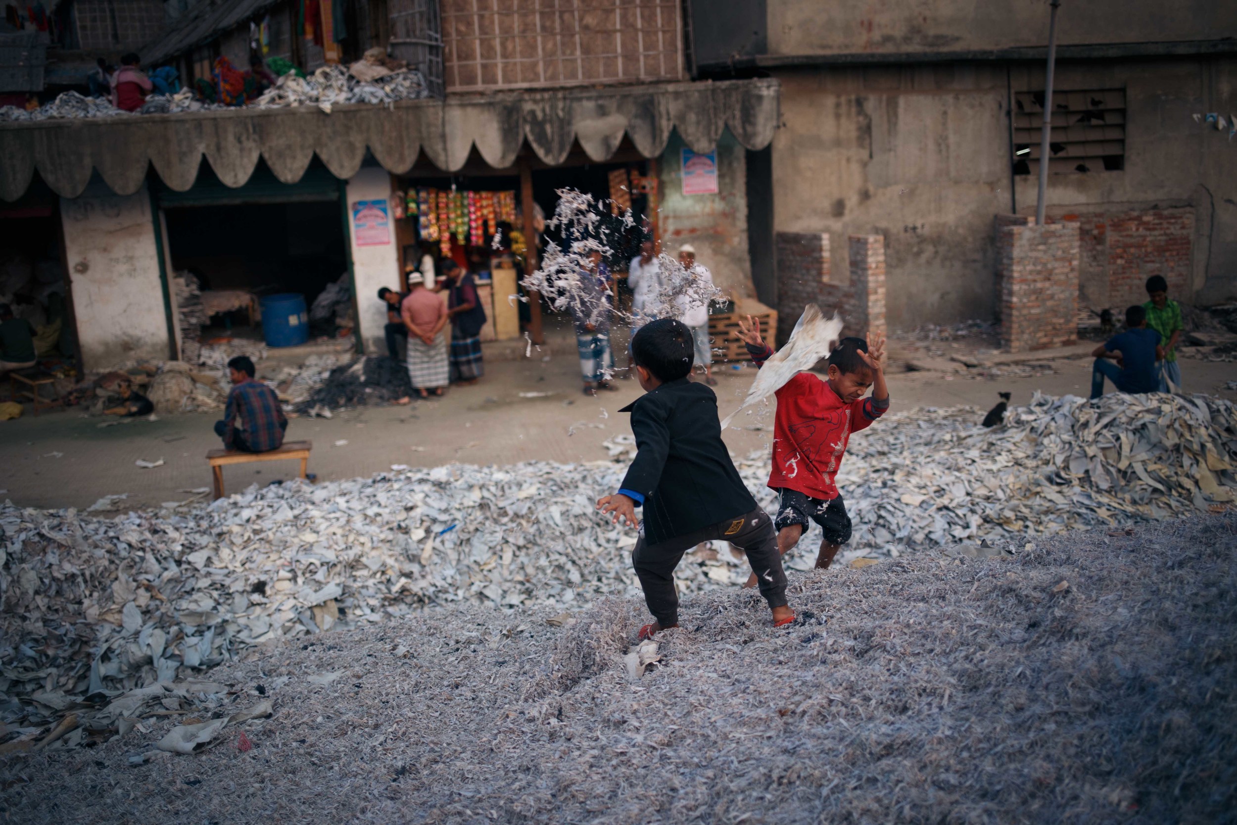  Children play among piles of discarded leather. 
