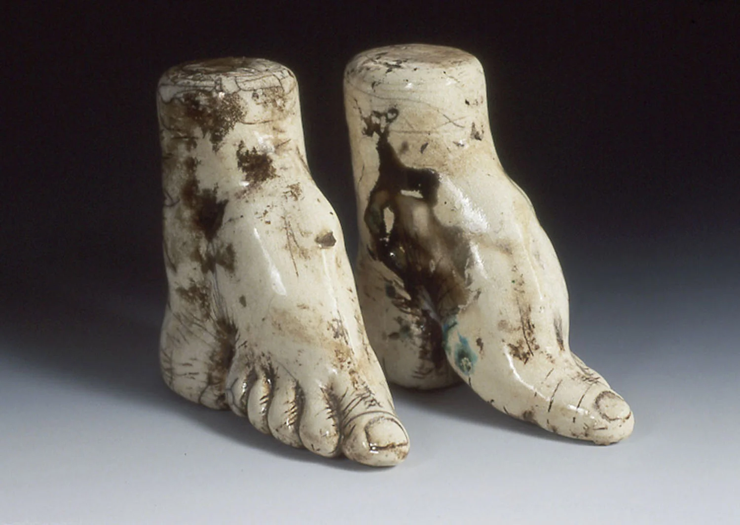 Bound to Please #23, an artwork by Lorna Stevens featuring two Raku-fired ceramic depictions of bound feet.