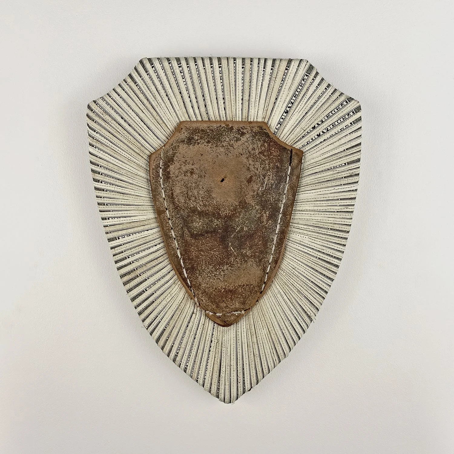 An award plaque-shaped artwork by Lorna Stevens made with U.S. currency, a worn shoe sole, and shoelace, honoring those who provide emotional and financial support to others.