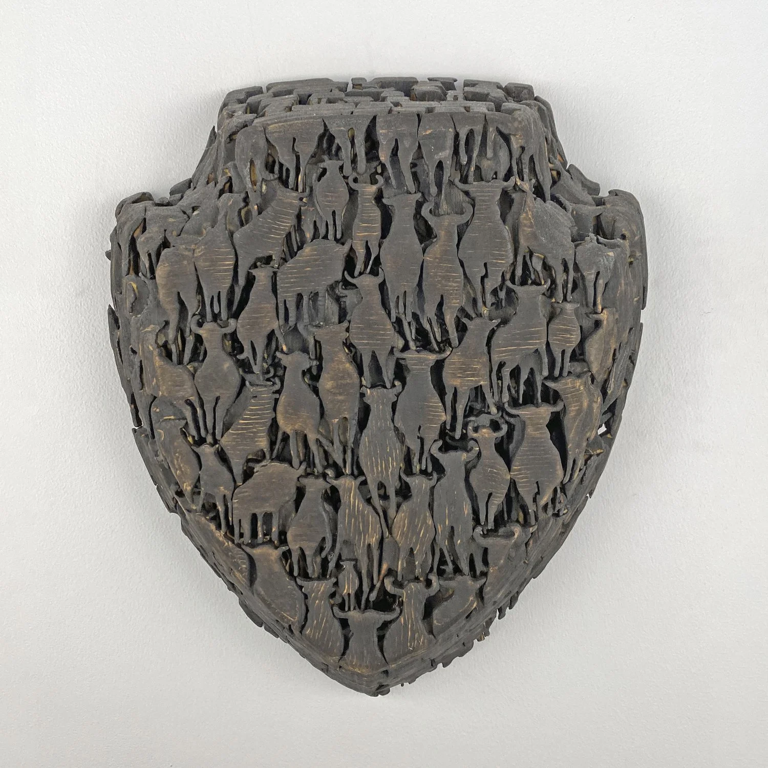 Herd, a small wall-mounted artwork by Lorna Stevens composed of charred wood forms suggesting a densely gathered herd of animals.