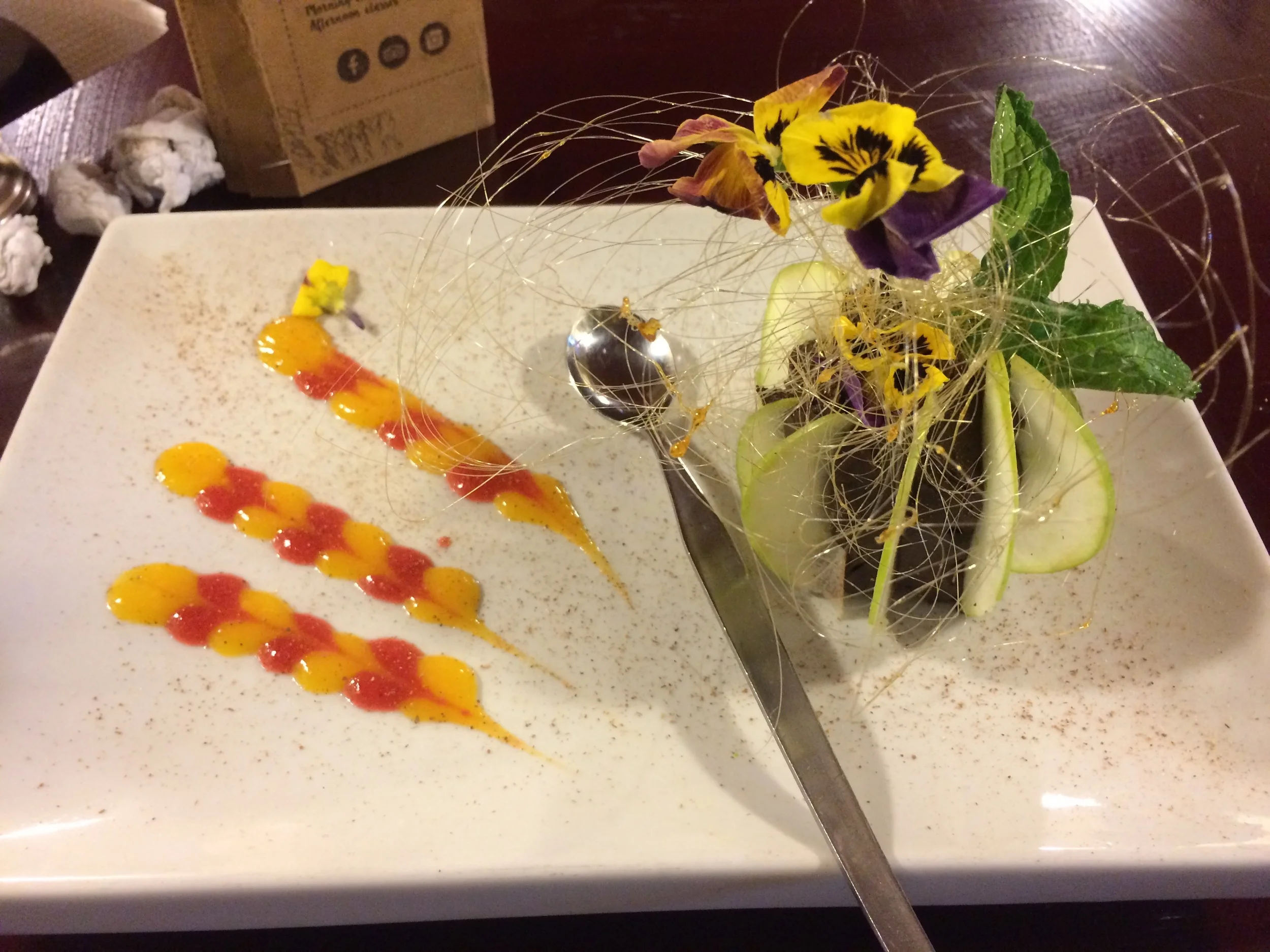 The fanciest chocolate mousse there ever was. It's decked out with green apple slices, edible flowers, and edible strands of gold. 