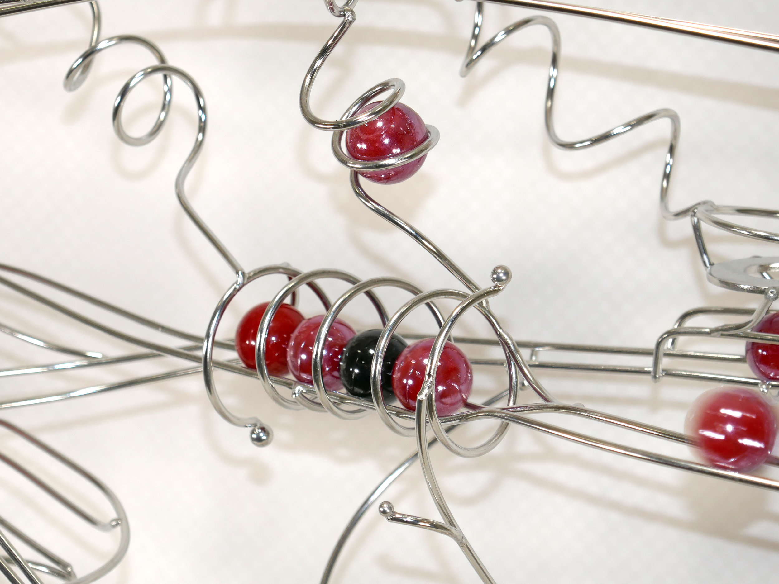 Rolling ball marble machine - close up of energy transfer kinetic element with red and black marbles
