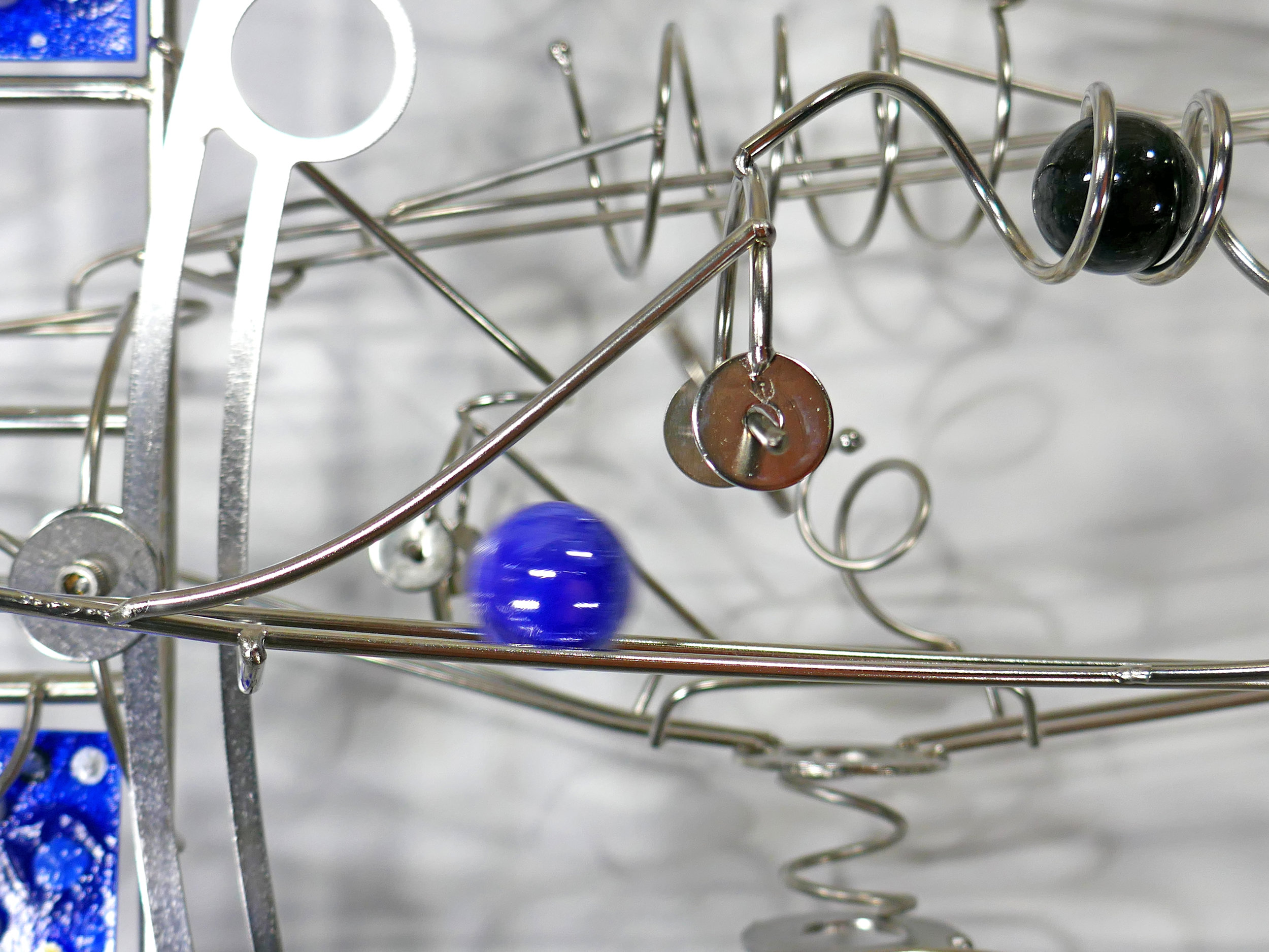 Rolling ball marble machine - close up of marble going down through a spinner element - Stephen Jendro
