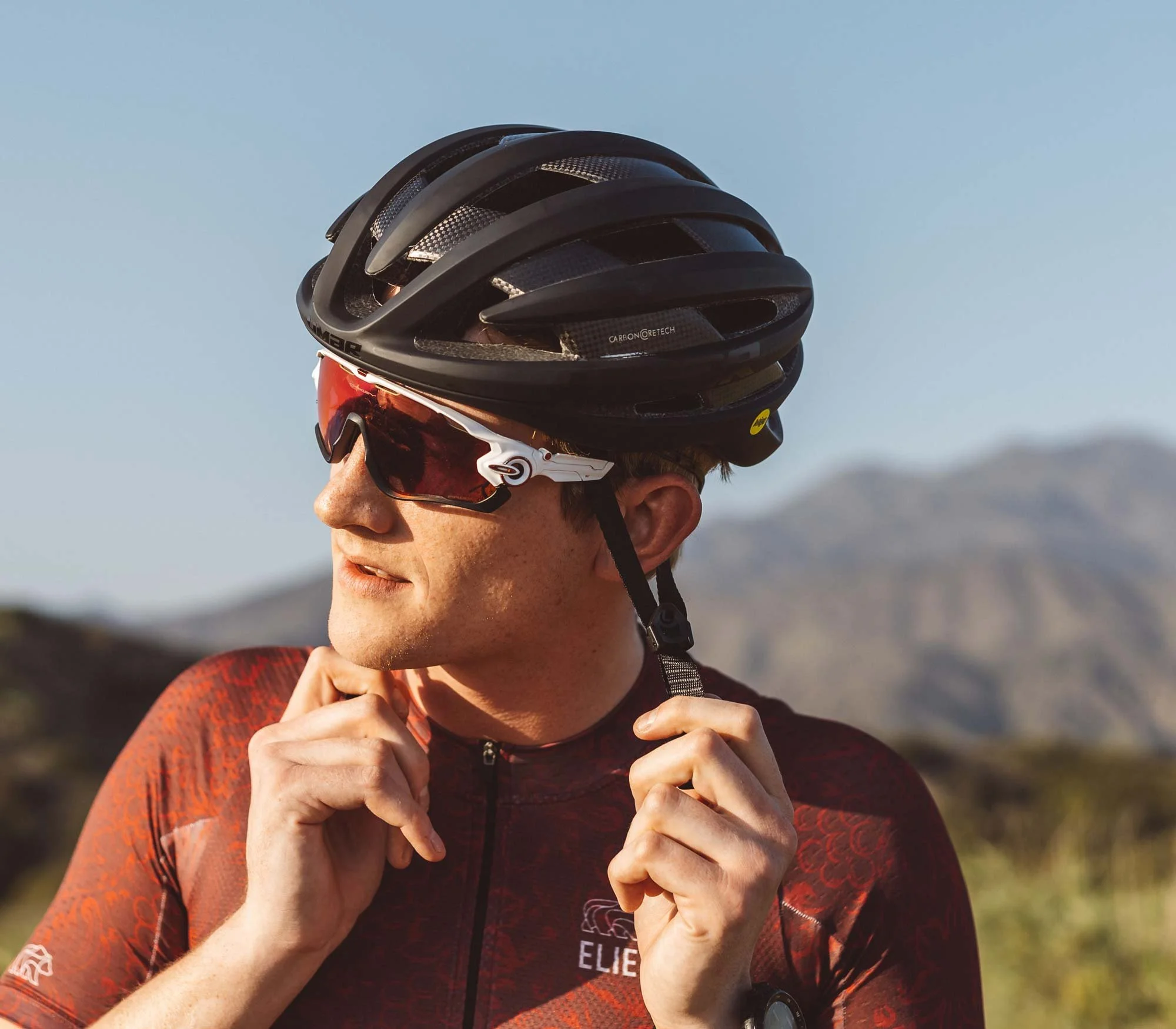 catalog photo of rider putting on cycling helmet