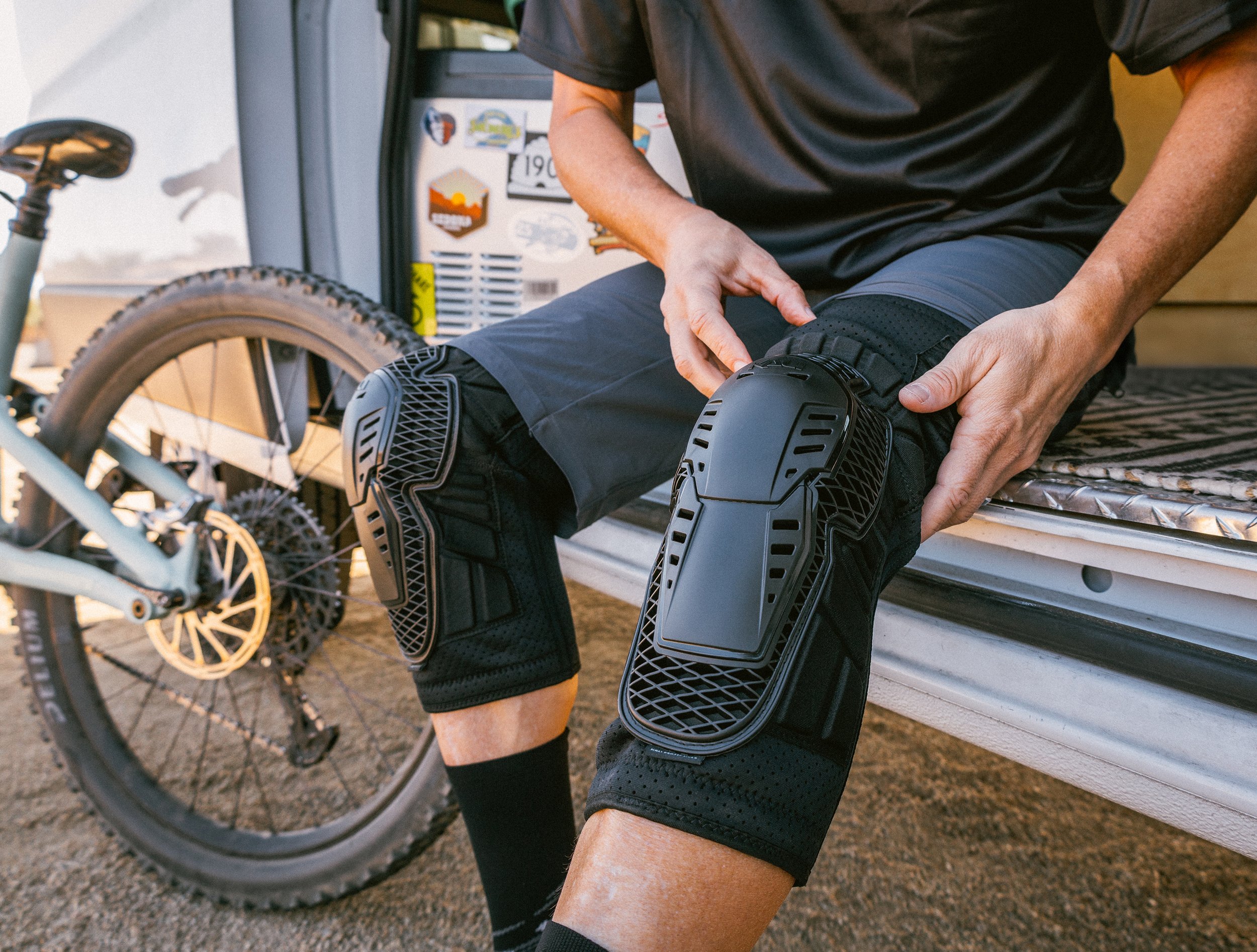 catalog photography of rider putting on protective gear with mountain bike