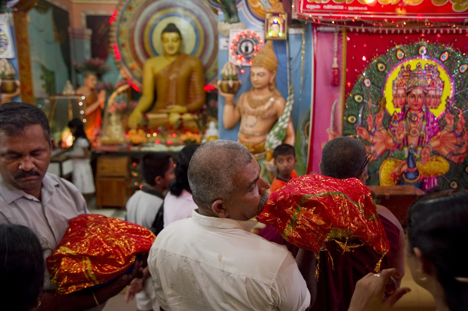 Pilgrims with offerings in Kataragama, Sri Lanka simultaneously worship Buddha and Lord Murugan, a Hindu god. The temple town is a regionally popular place of pilgrimage of Hindu, Buddhist, Muslim and indigenous Vedda communities of Sri Lanka and South India, where the god Muruga is the main deity.