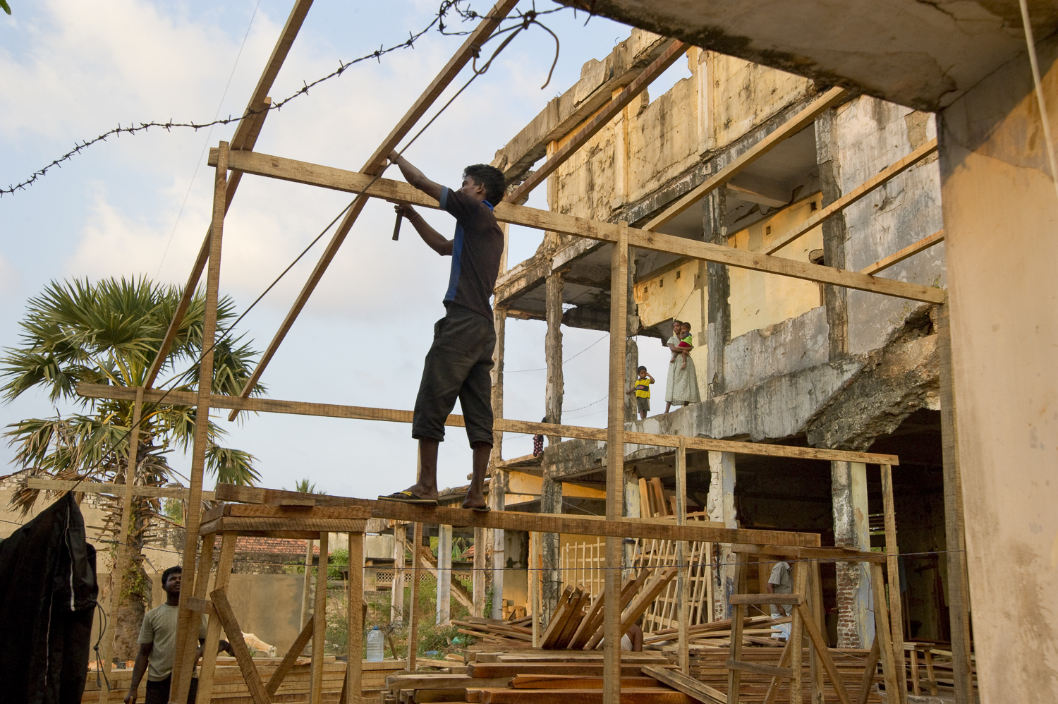   Near downtown Jaffna, locals construct a wood-shed in the remnants of war-destroyed housing. As new building materials are imported from the south, Jaffna is showing signs of development and new investments.  