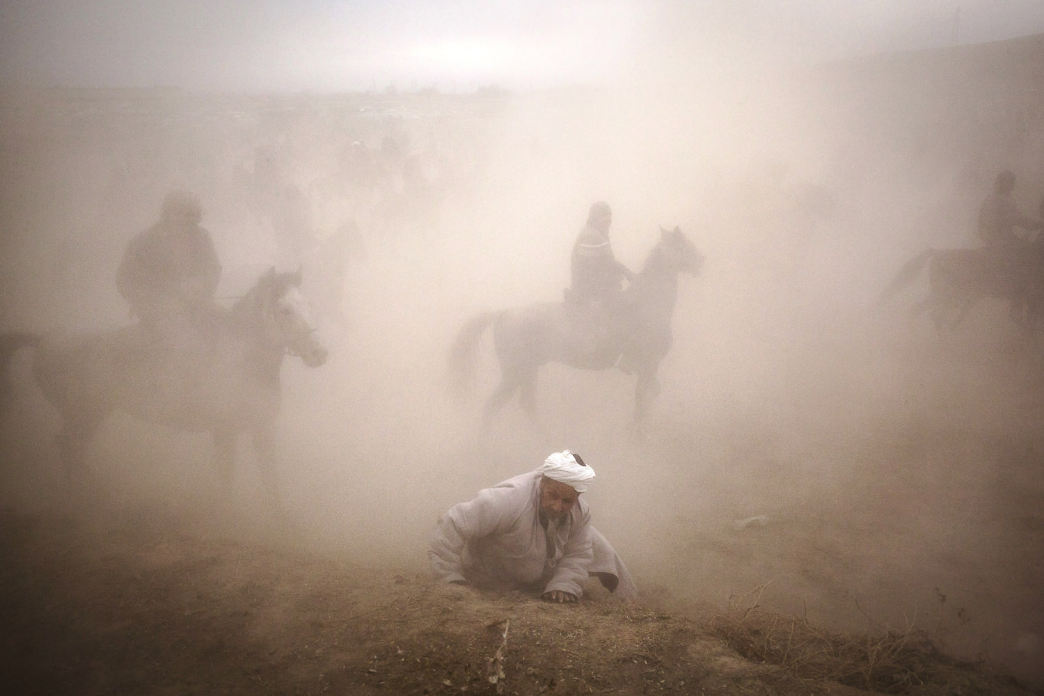  Too slow to jump to a retreat with the rest of the audience, an old man is lost in the dust of a horde of buzkashi horses. Near Sharinav, Tajikistan. Popular throughout much of Central Asia, buzkashi is a form of horse polo in which horseback player