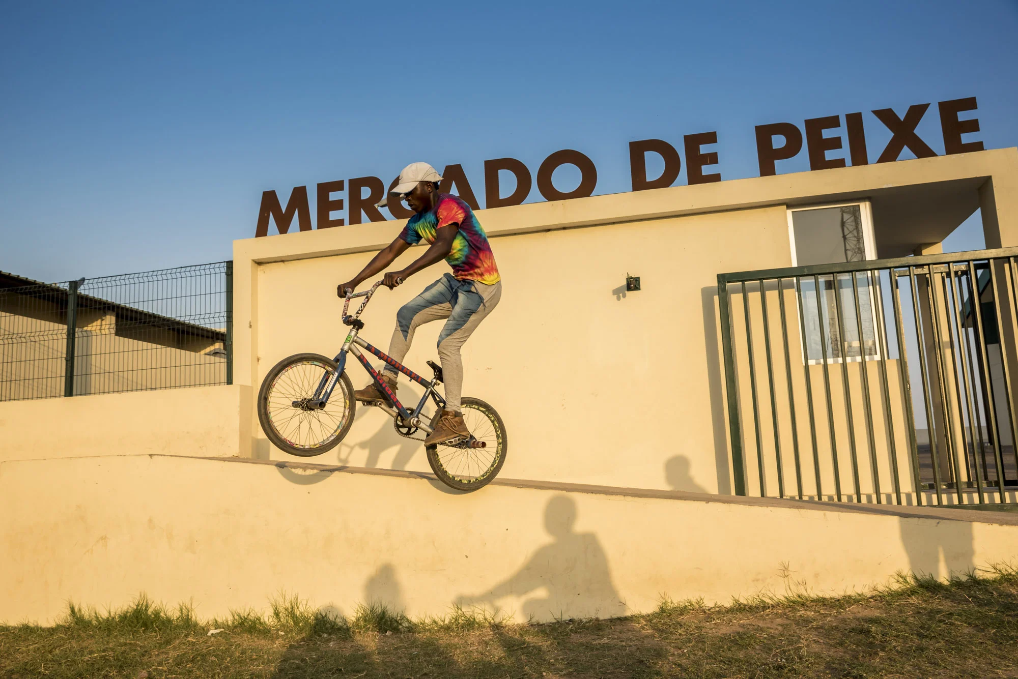 Boy jumping with his bicycle in front of the Fish Market entrance, Maputo, Mozambique, 21/08/2016 © Dosfotos