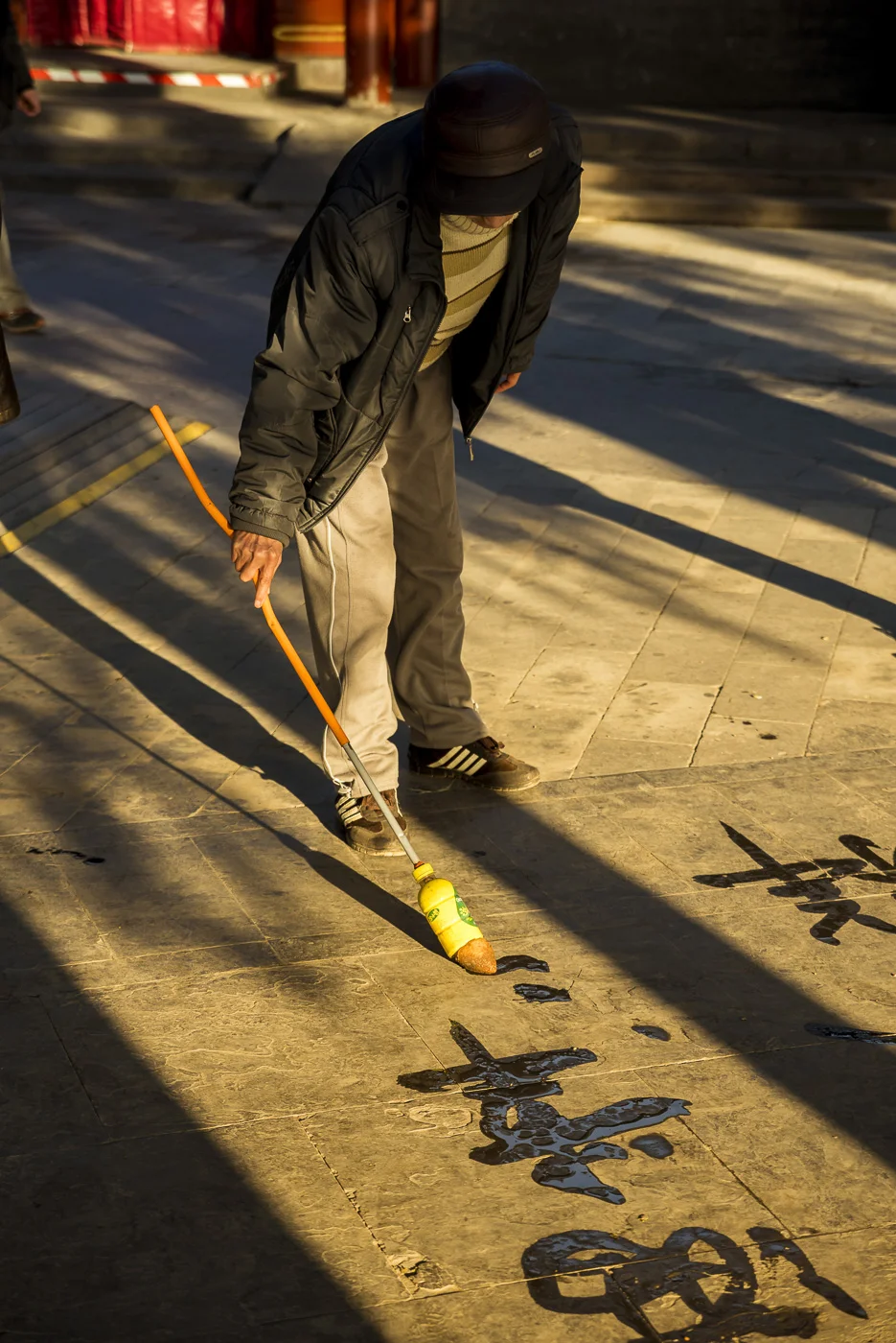 Man writing oversized calligraphy on the floor, The Summer Palace, Beijing, China © Dosfotos