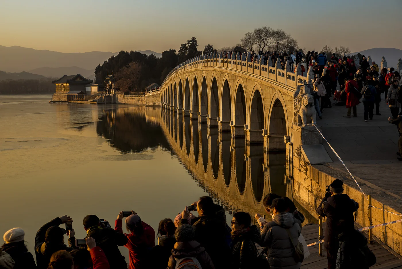 Crowd of tourists taking photographs of the 17 Arch Bridge at sunset, The Summer Palace, Beijing, China © Dosfotos