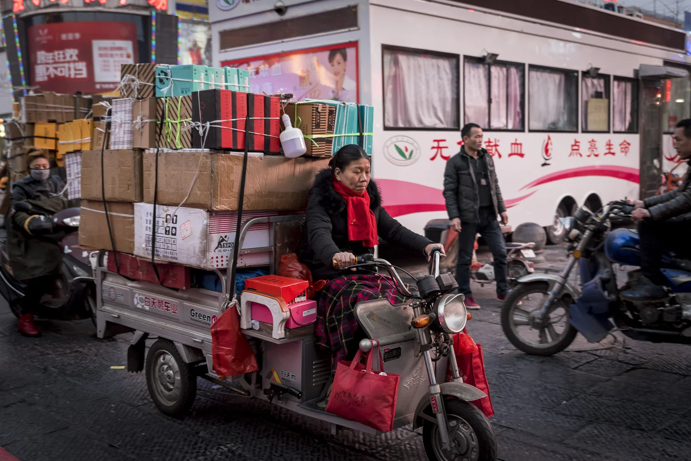 Chinese woman riding a bike loaded with boxes in Luoyang Old Town District, Henan Province, China © Dosfotos