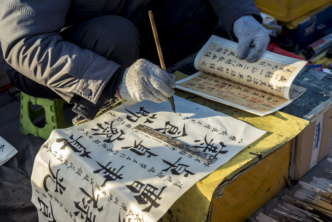 Art brushes vendor practicing calligraphy in Panjiayuan Antique Market, Beijing, China © Dosfotos