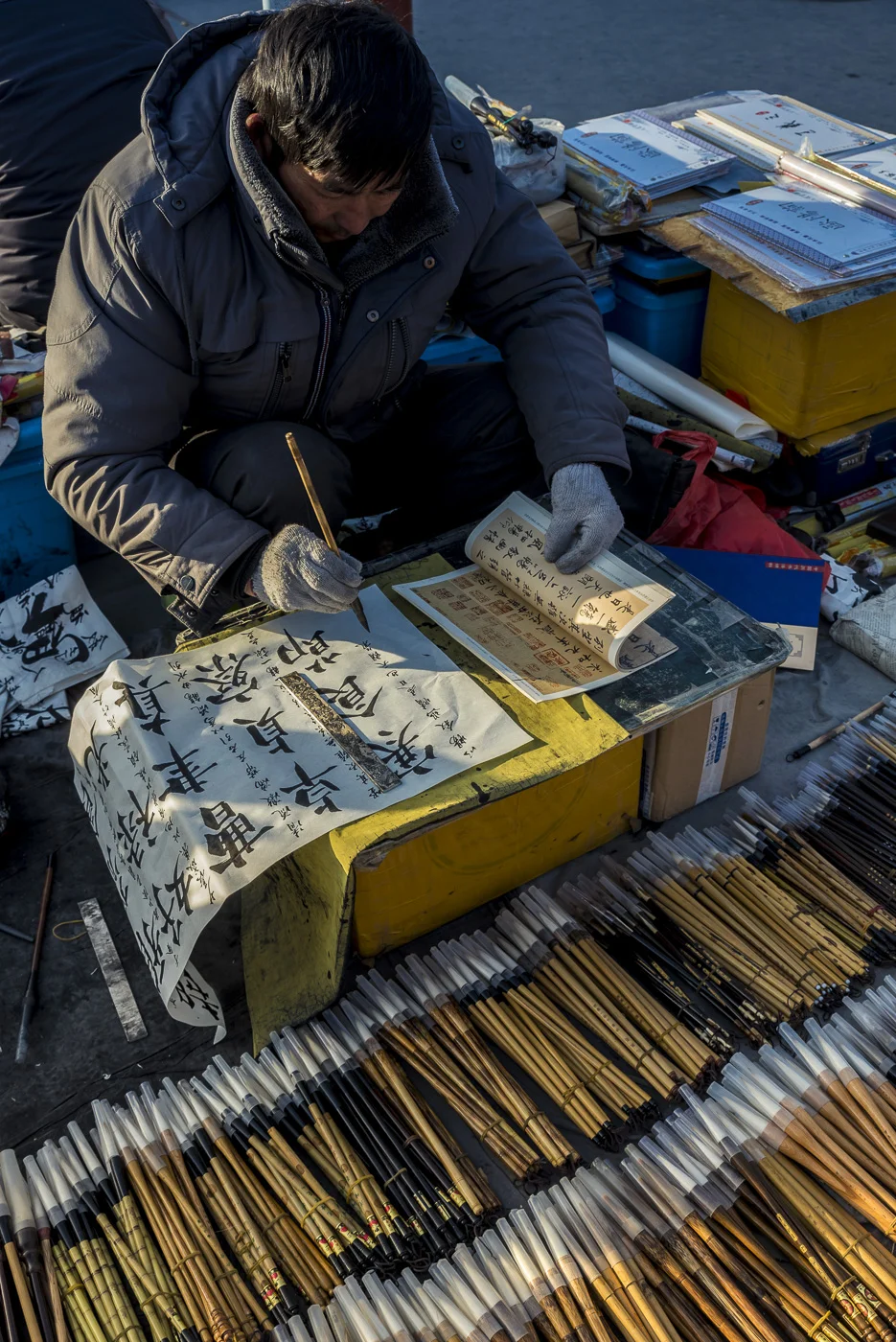Art brushes vendor practicing calligraphy in Panjiayuan Antique Market, Beijing, China © Dosfotos
