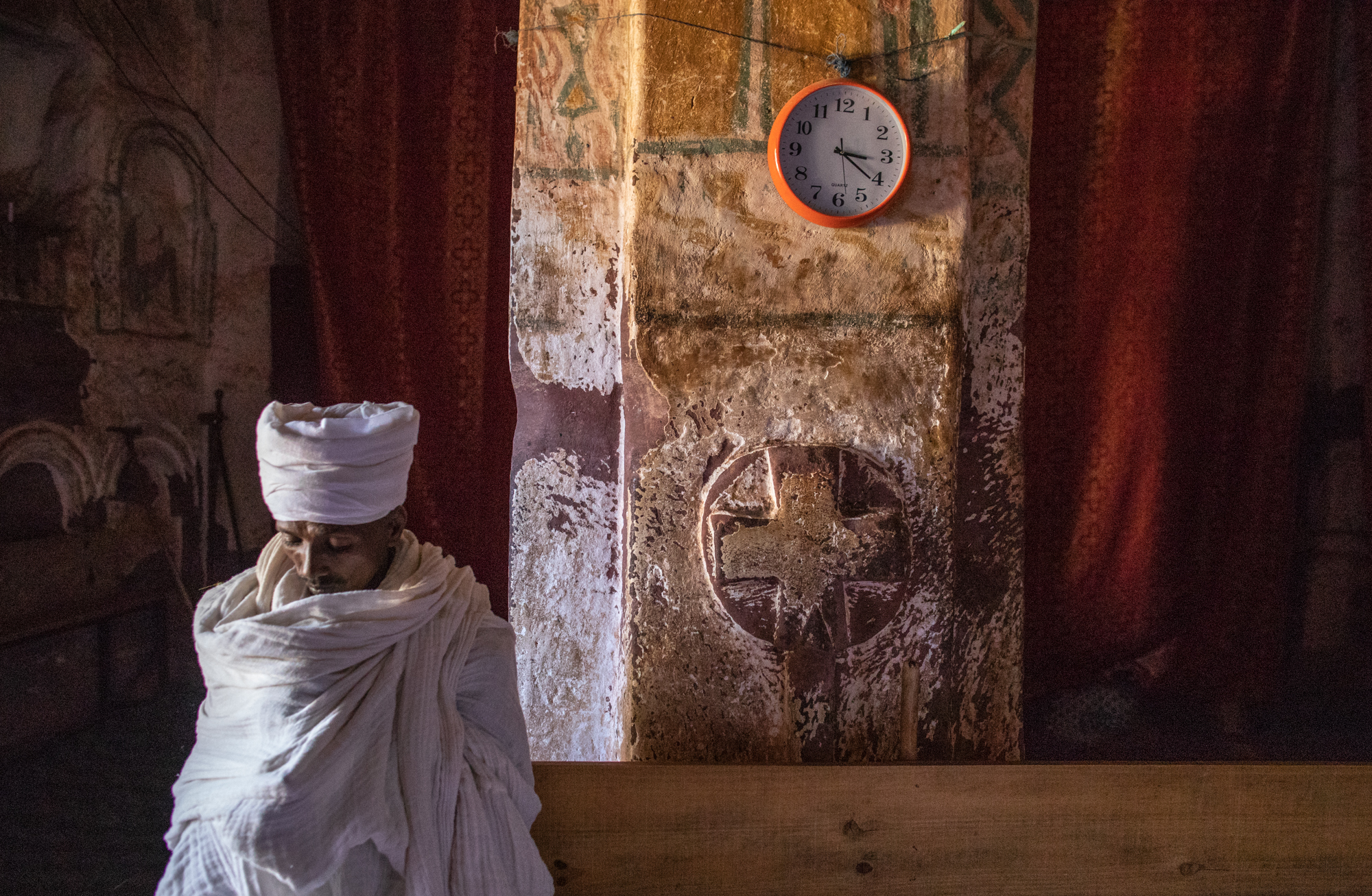   Debra Zion Chruch in Abuna Abraham, Ethiopia -  A priest sitting in the magnificent rock-hewn church known for its architectural features, including decorated dome ceilings, bas-reliefs, and carved crosses on the walls. Access to the church involve