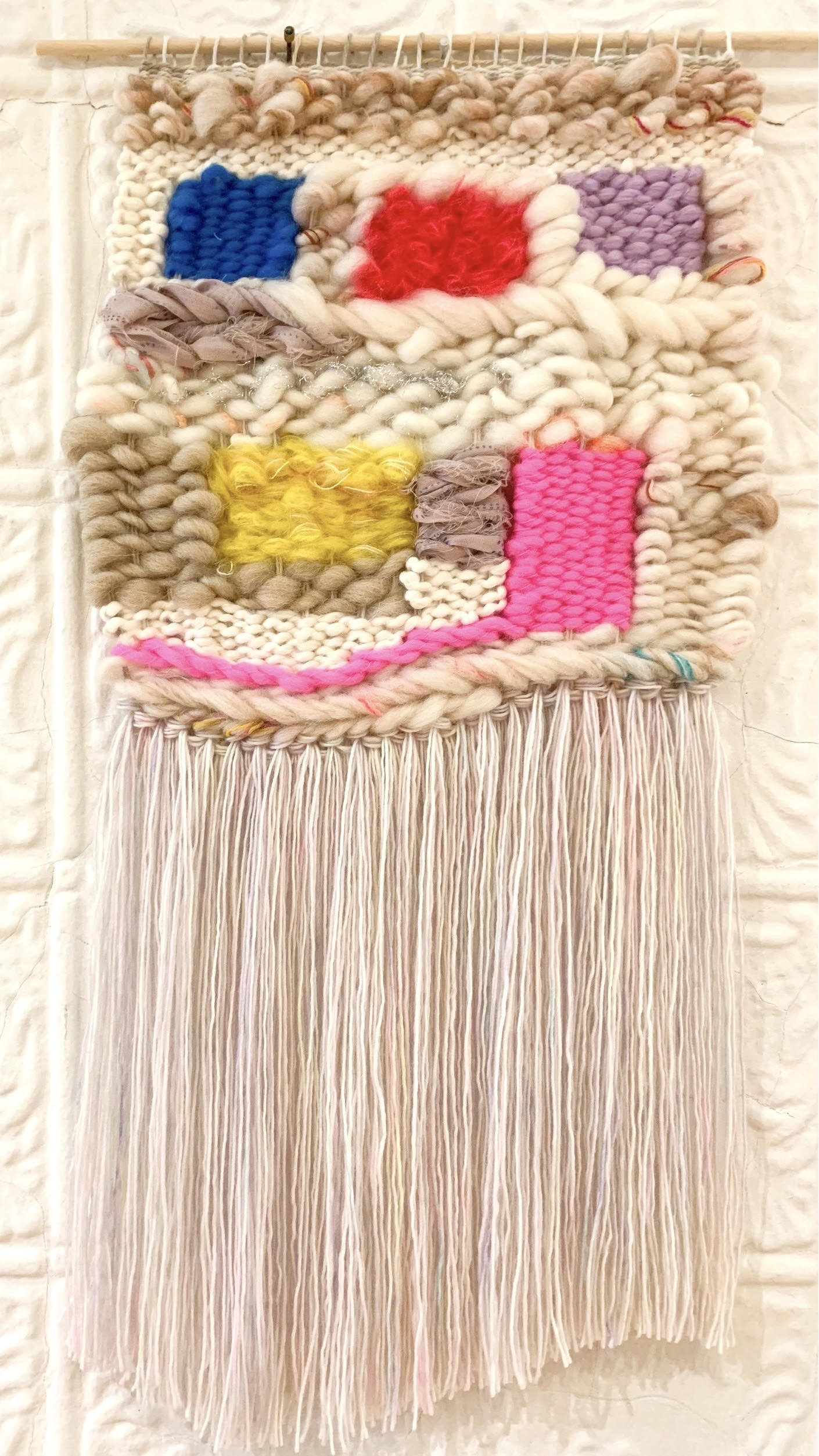 off white and beige woven tapestry with blue, red, purple, yellow and pink squares.