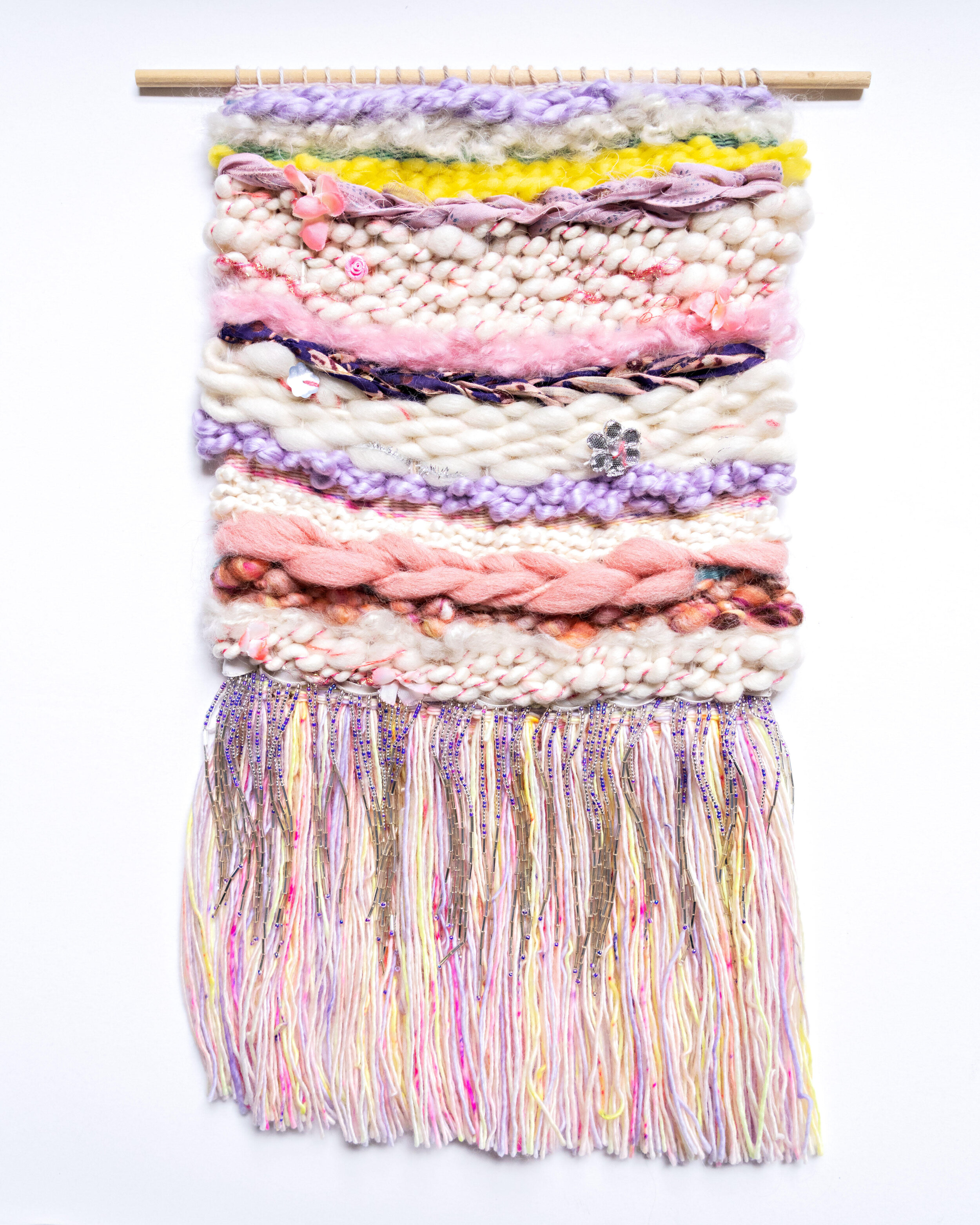 wool and cotton woven tapestry in white, pink, yellow, and purple with beaded fringe