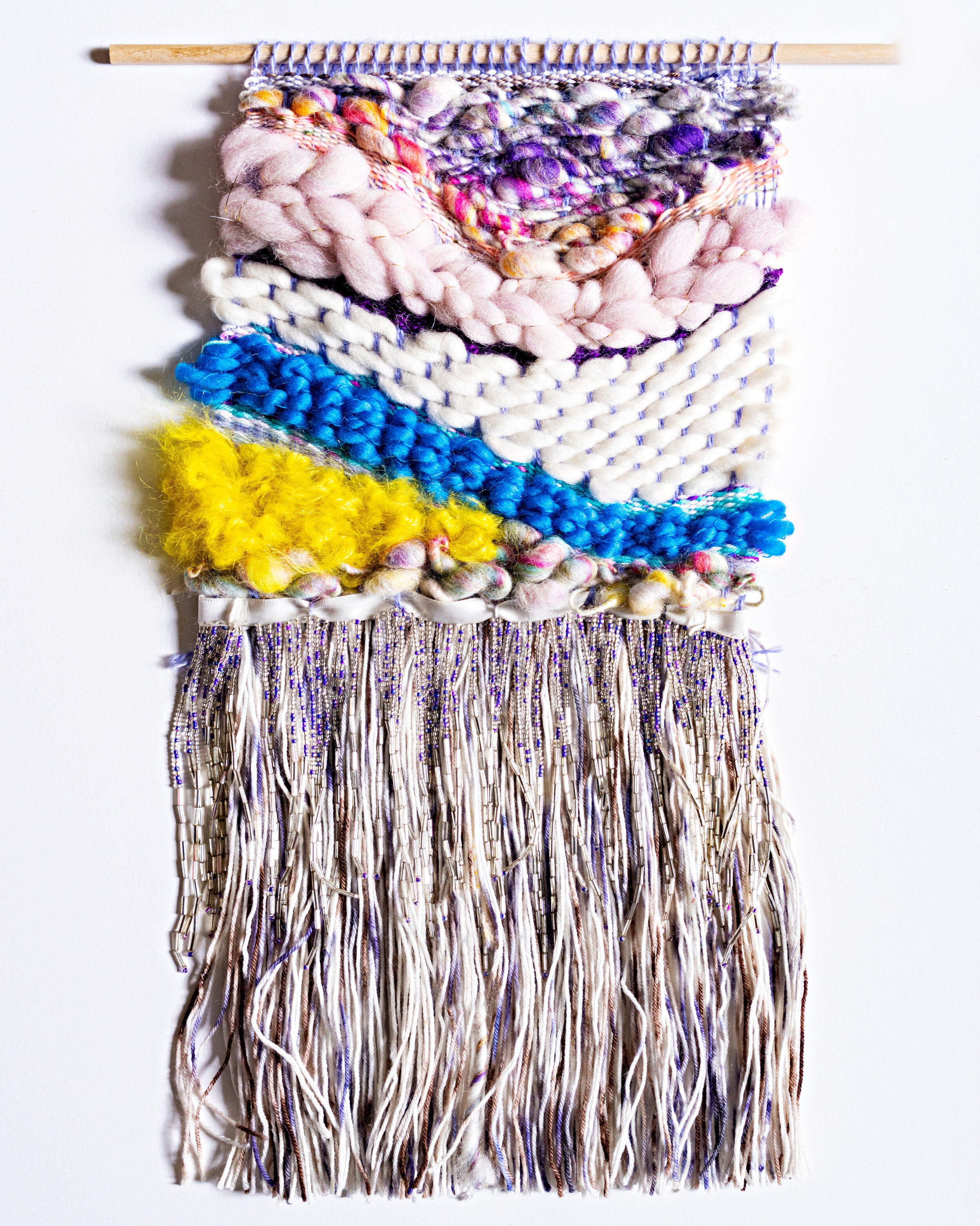 knit yarn tapestry in blue, yellow, white, purple, and beads