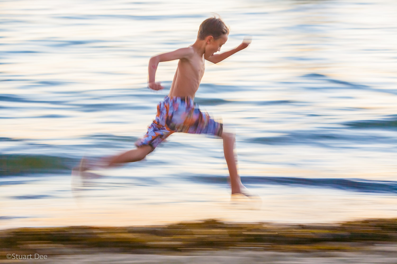  Young boy running along the beach at sunset,  Vancouver, BC, Canada 