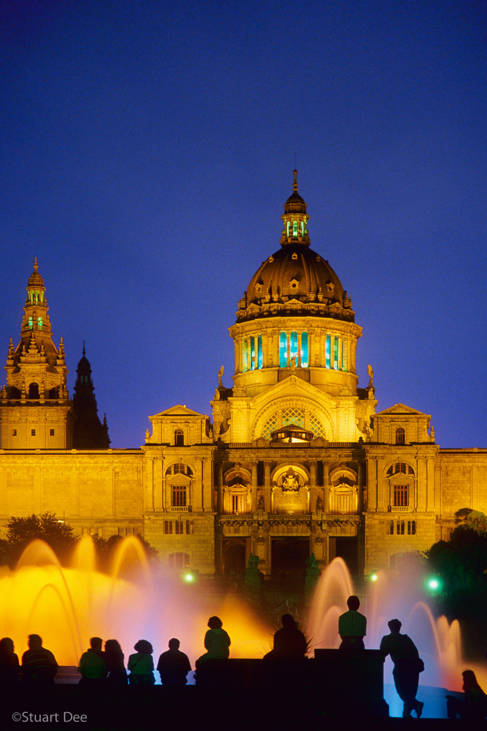  People watching water fountain show in from of Montjuic Fountain and Montjuic Palace, at night, Barcelona, Spain 