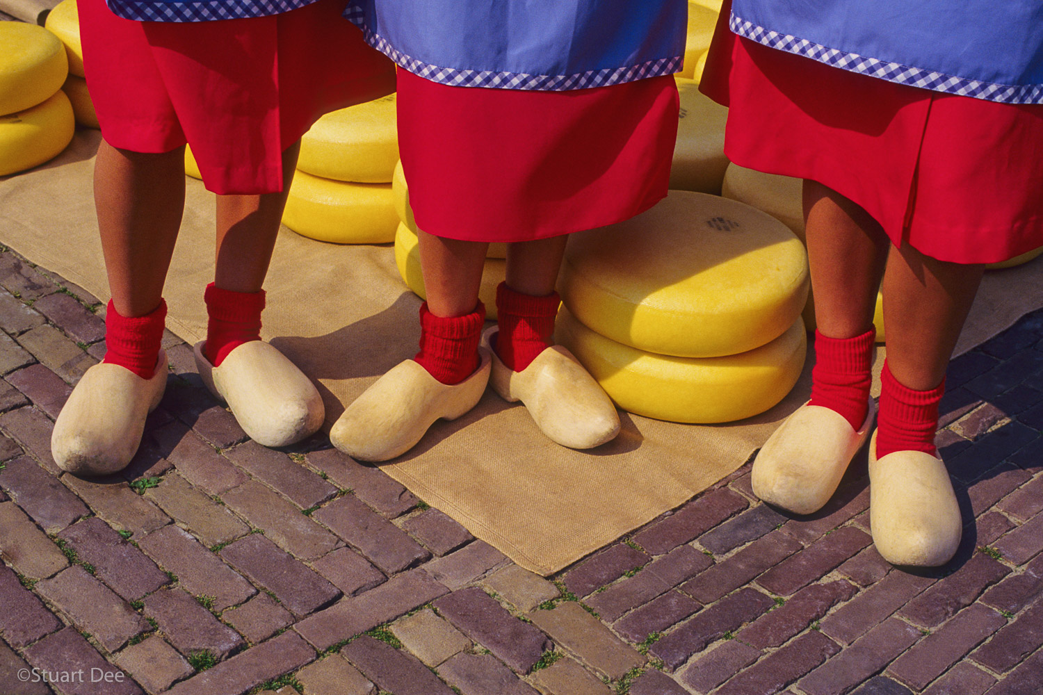  Three young Dutch women wearing wooden clogs, in front of cheese, Alkmaar Cheese Market, Alkmaar, Holland  The Alkmaar Cheese Market is unique in the world. 