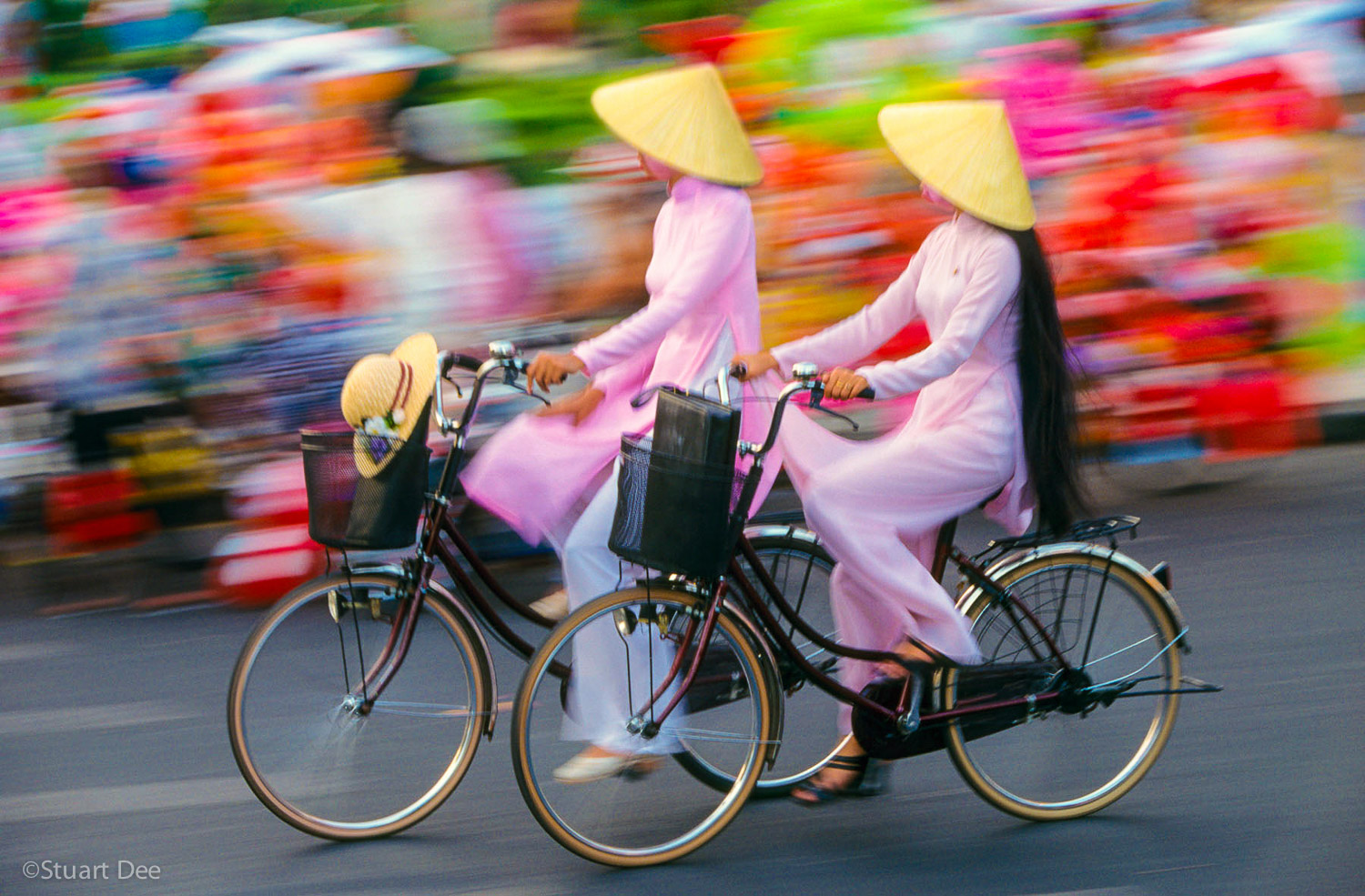 Two women wearing ao dais, on bicycles, Ho Chi Minh City, Vietnam