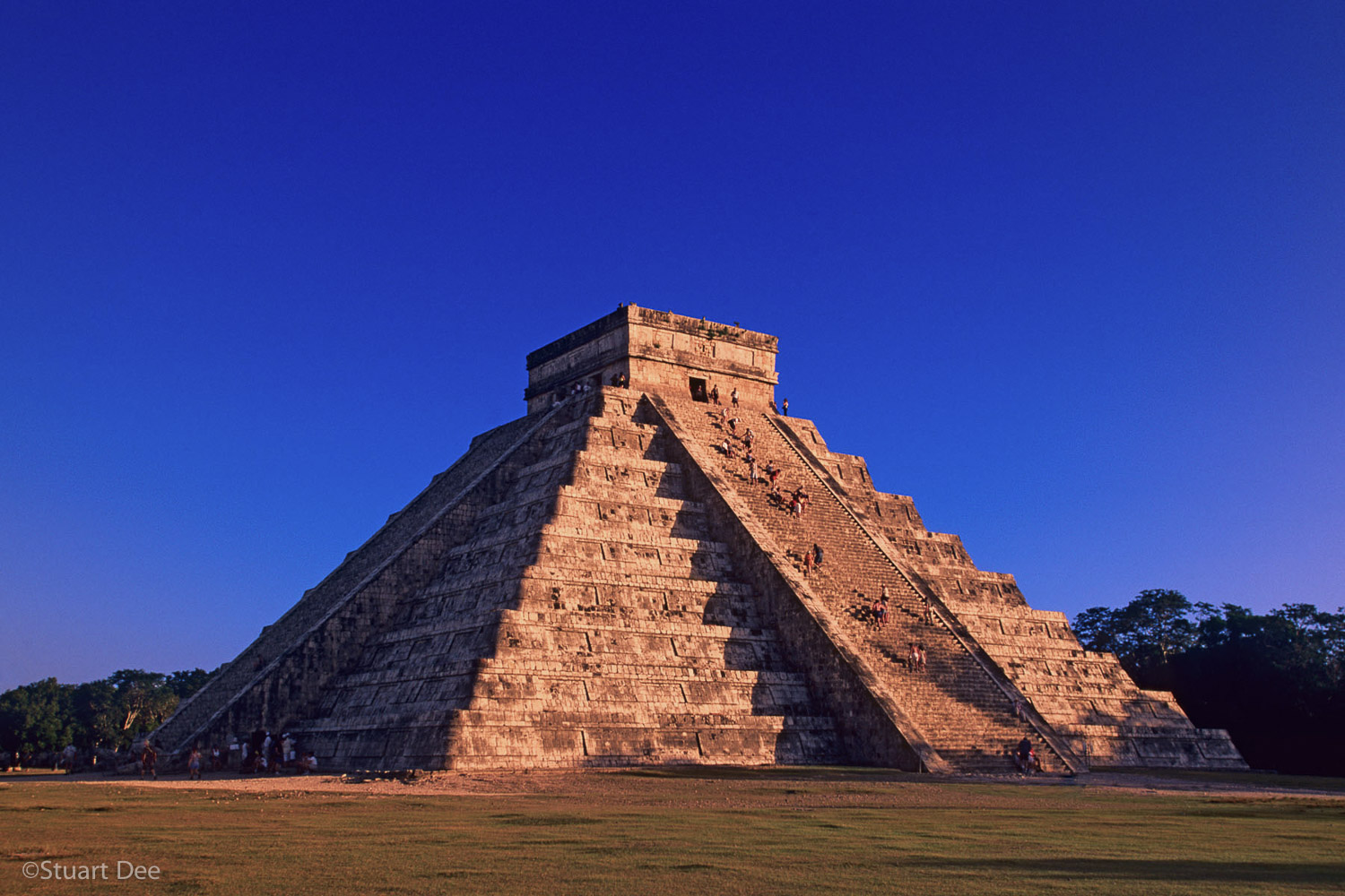 Mayan Pyramid of Kukulkan, (El Castillo or The Castle) at sunset, with some tourists climbing to the top, Chichen Itza, Mexico