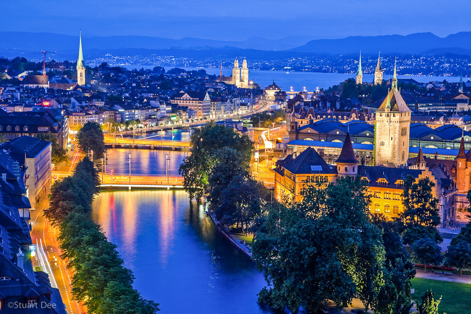  Aerial view of city skyline at dusk/night, Zurich, Switzerland. This view shows the Limmat River and Lake Zurich, and the spires of the most prominent churches. Zurich is the largest city in Switzerland, and is its commercial, banking, and cultural 