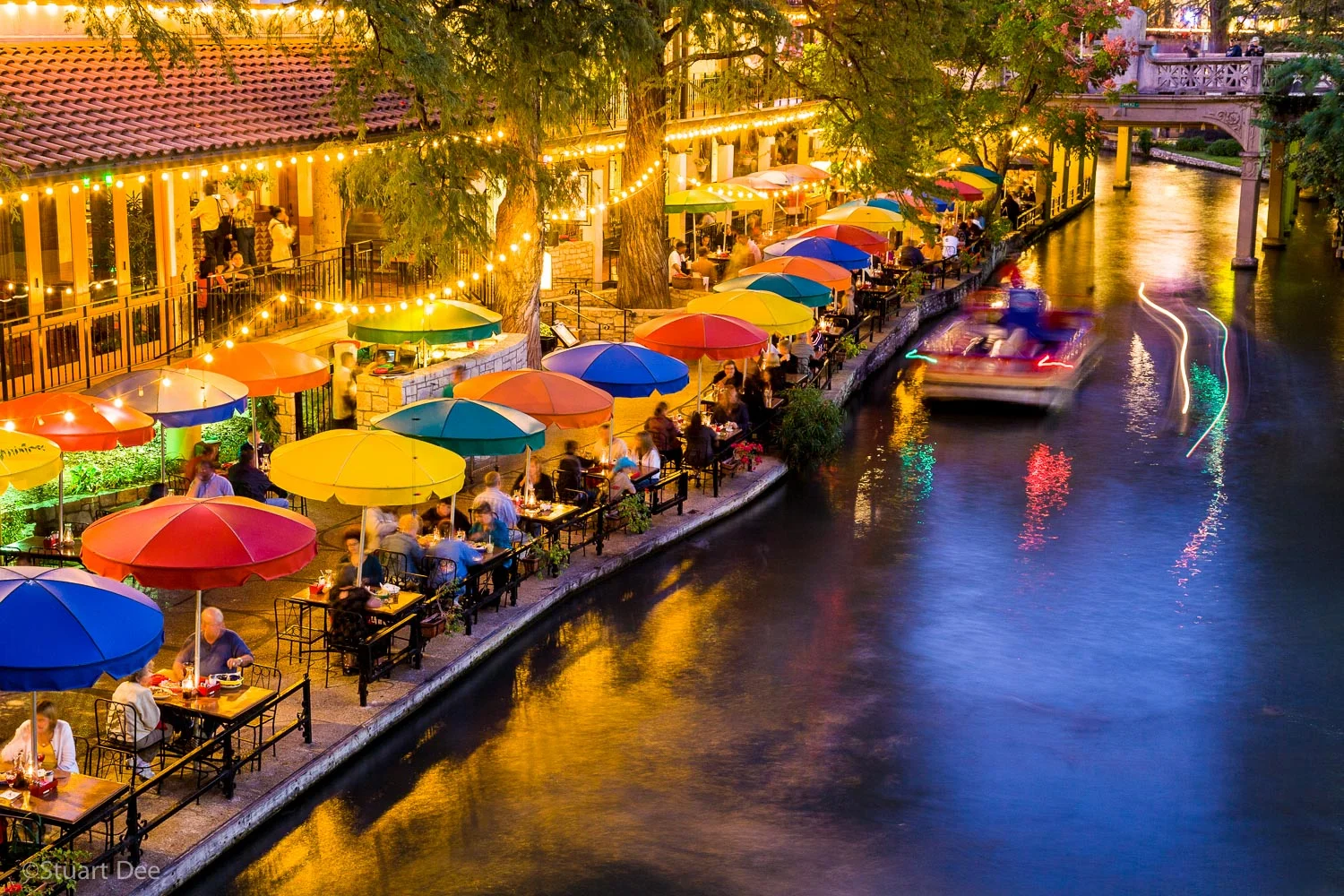 People dining at outdoor terrace at the San Antonio Riverwalk at sunset/dusk/evening/night, San Antonio River Walk, San Antonio, Texas, USA. The River Walk is the most popular tourist atrraction in the city.