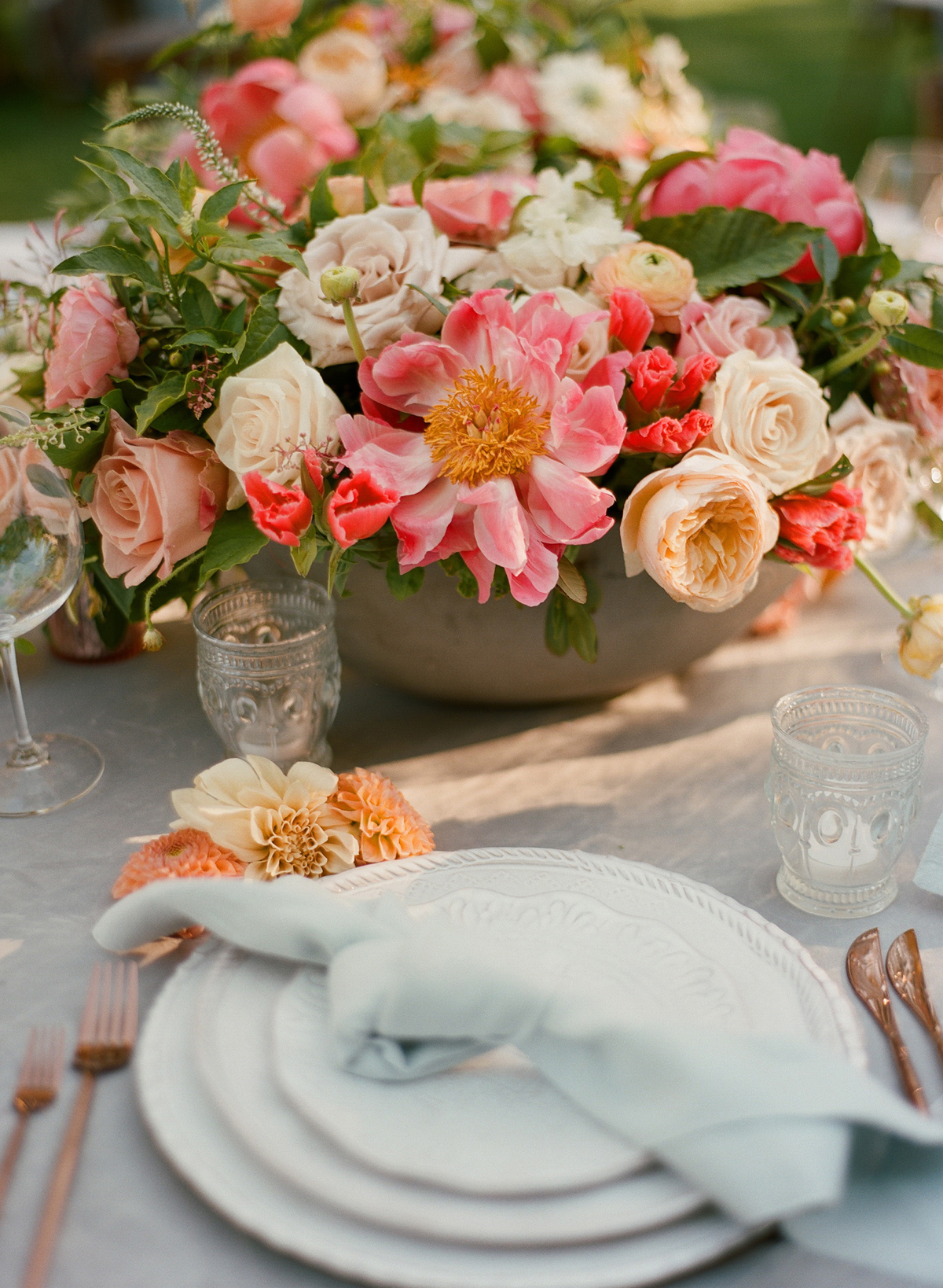 Photography . Christina McNeill. The added touch of flowers on the tables was the planner's idea. And it's a good one. I love the way the china, the flatware and that knotted napkin worked together with those Peonies and dahlias. Executing this event with one team member down was harder than I could have imagined because of the extreme heat but getting there early is a key for getting things done on time. You need extra time when the weather is hot because everyone slows down a little, when the space is vast(trying walking in all black clothing with two garlands down 200 yards to the golf course when it's over 105), when the elements are against you. 