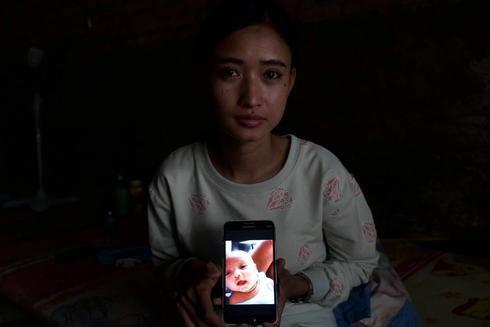 Erisa showing a picture of her son, Fiki, who passed away in 2013 due to lung disease (2017). Photo: Ardiles Rante