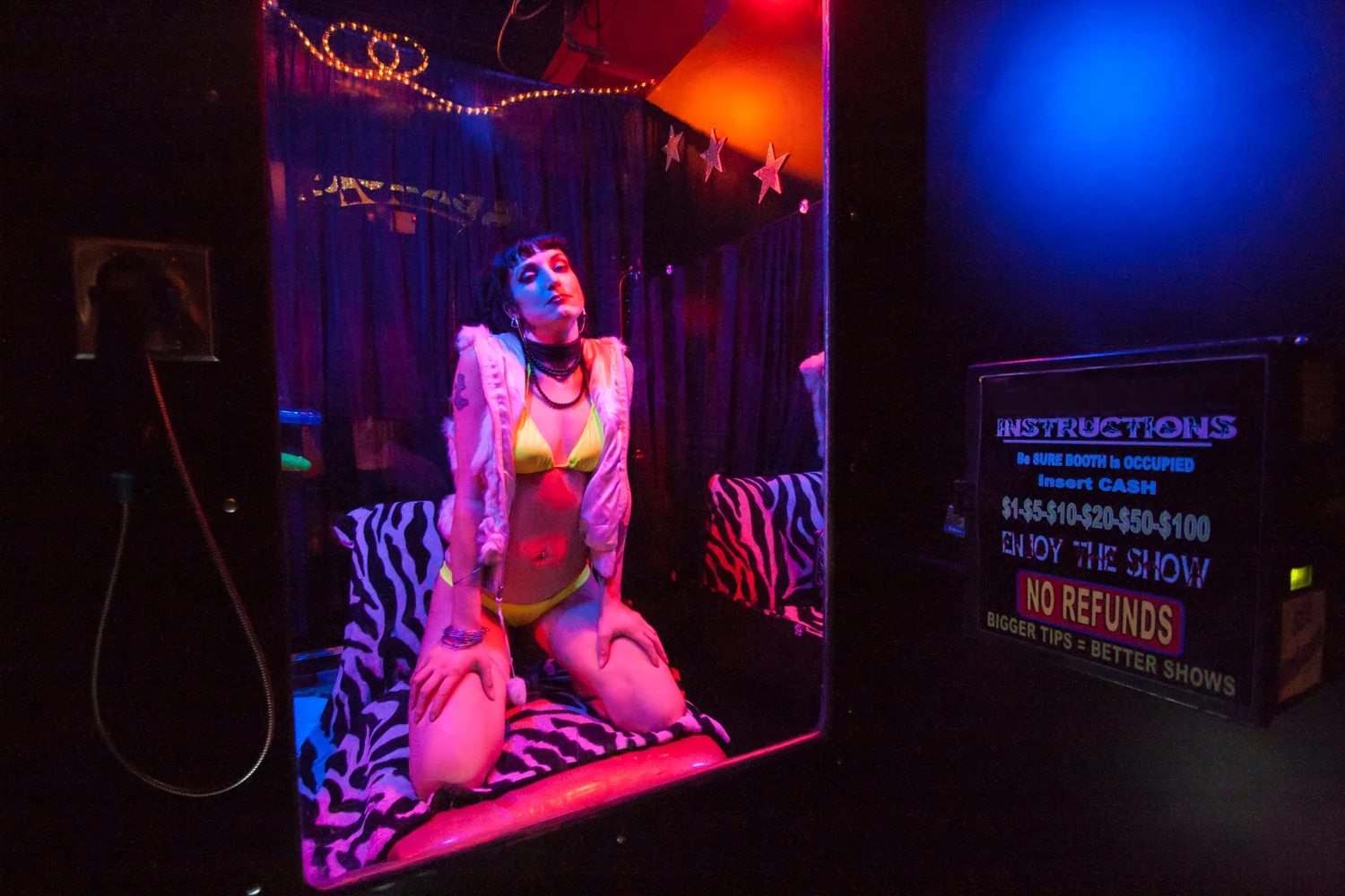 Jezebel, a live peep show performer, poses in her booth
