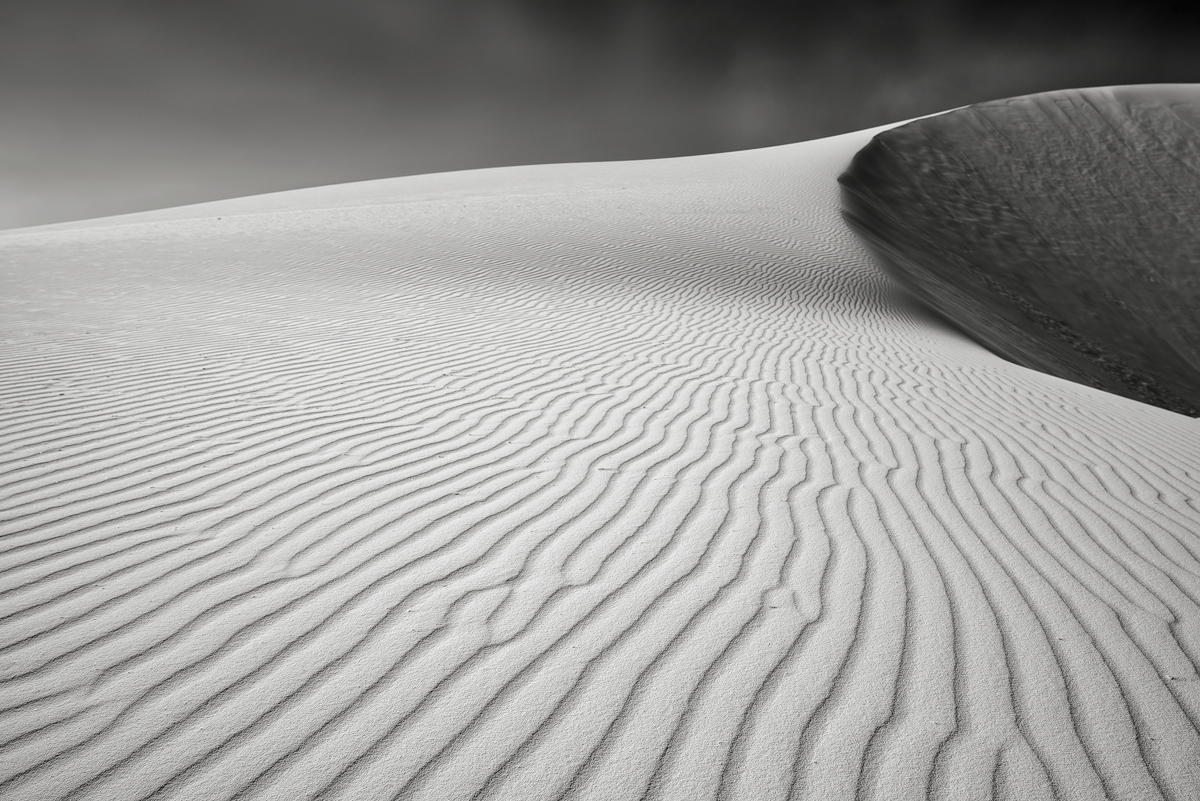 Ripples of sand lead the eye up towards the crest of a large dune.