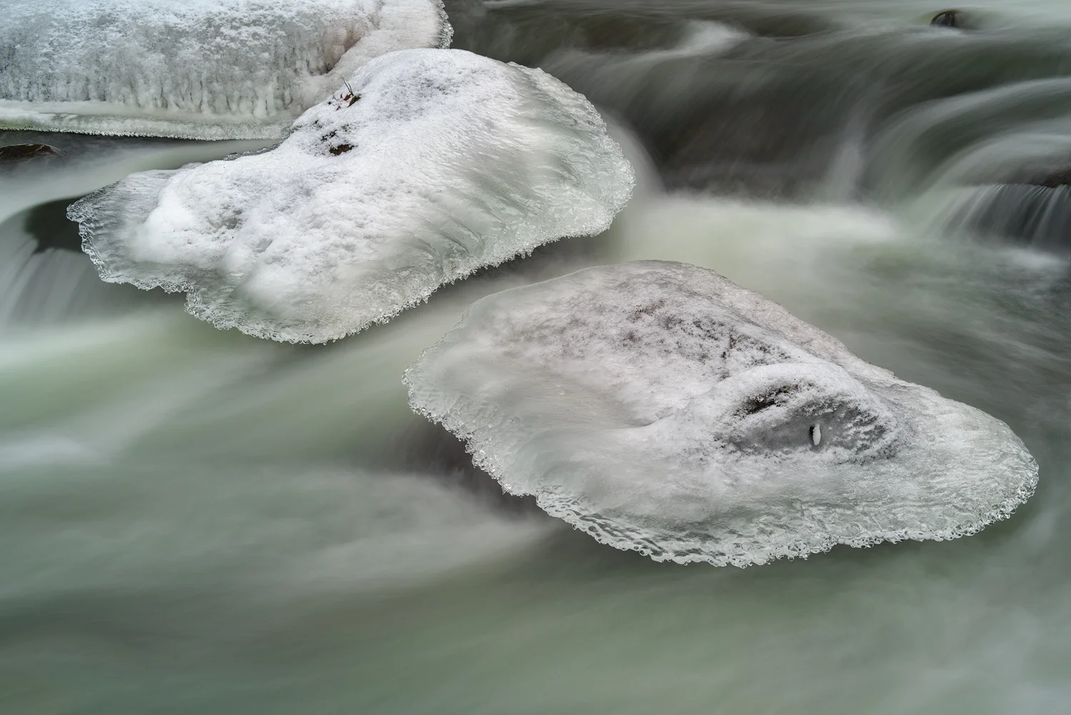 Winter ice forms over top of rocks within the icy flow.