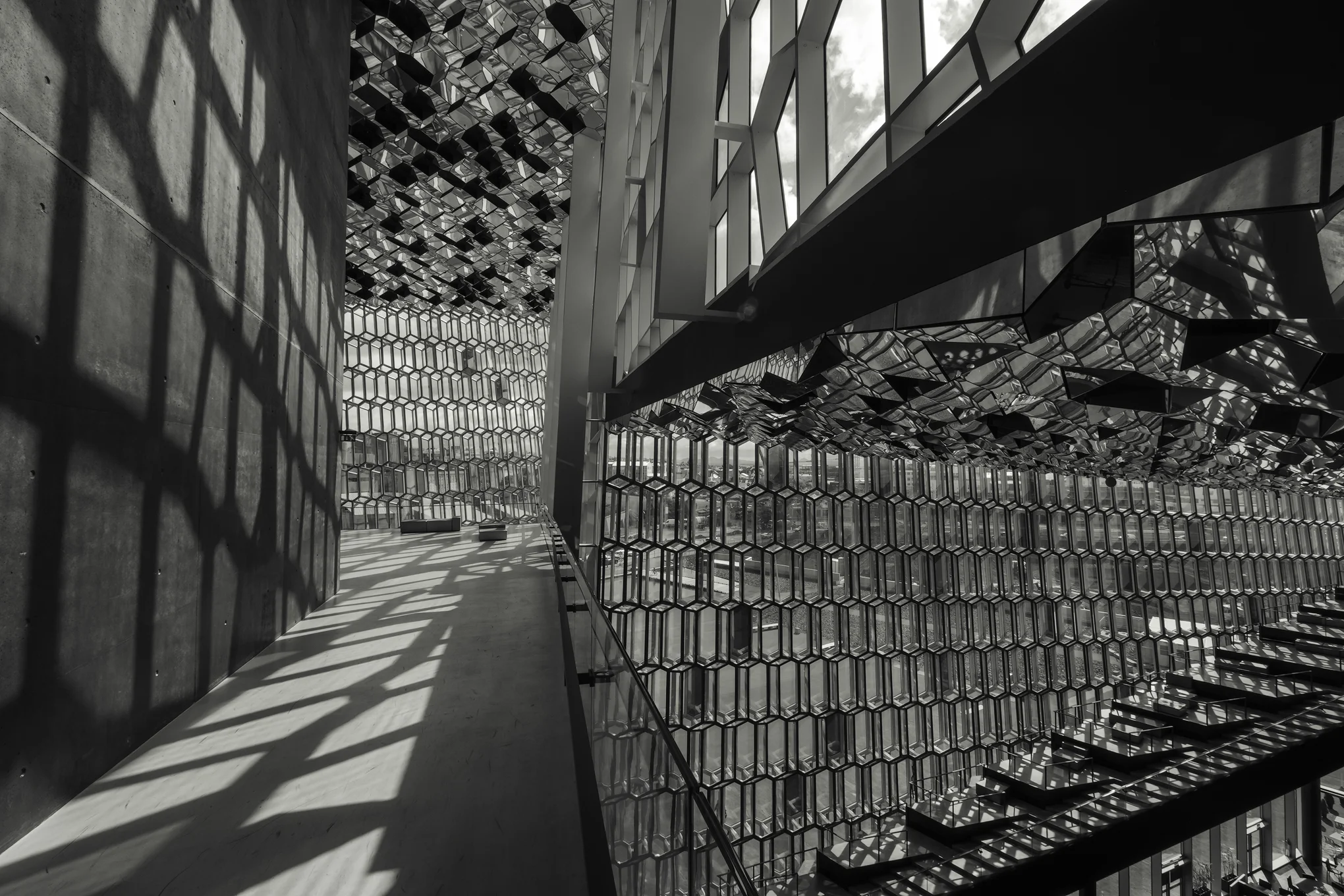 A walkway along the buildings core reflects patterns of light and shape from the windows.
