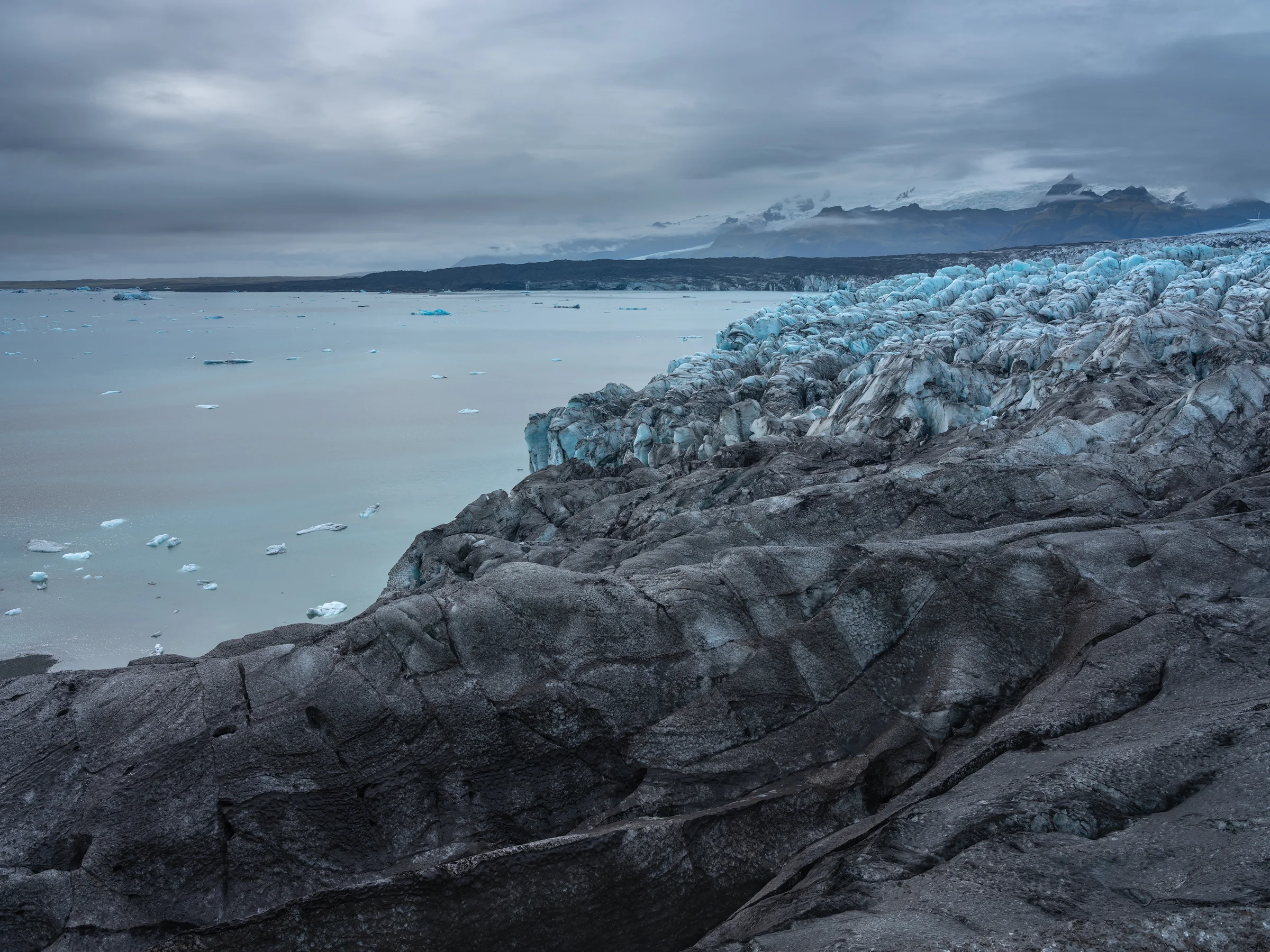 Black ridges of ice give way to the ice seracs that feed the glacial lagoon.