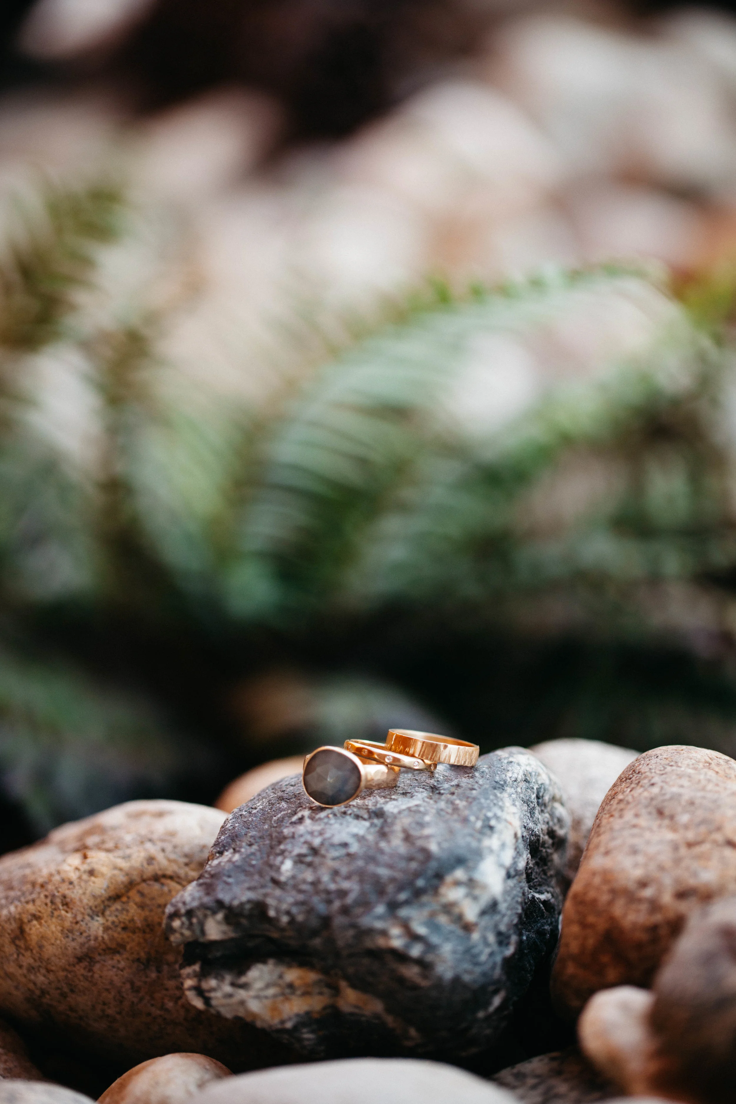 Rings by Leslie & Jared: 18k yellow gold; 4mm textured flat band, 2.5mm faceted half round band with flush set diamonds, and organic shap ed rose cut sapphire on a hammered band. Photo by Tim Kressin