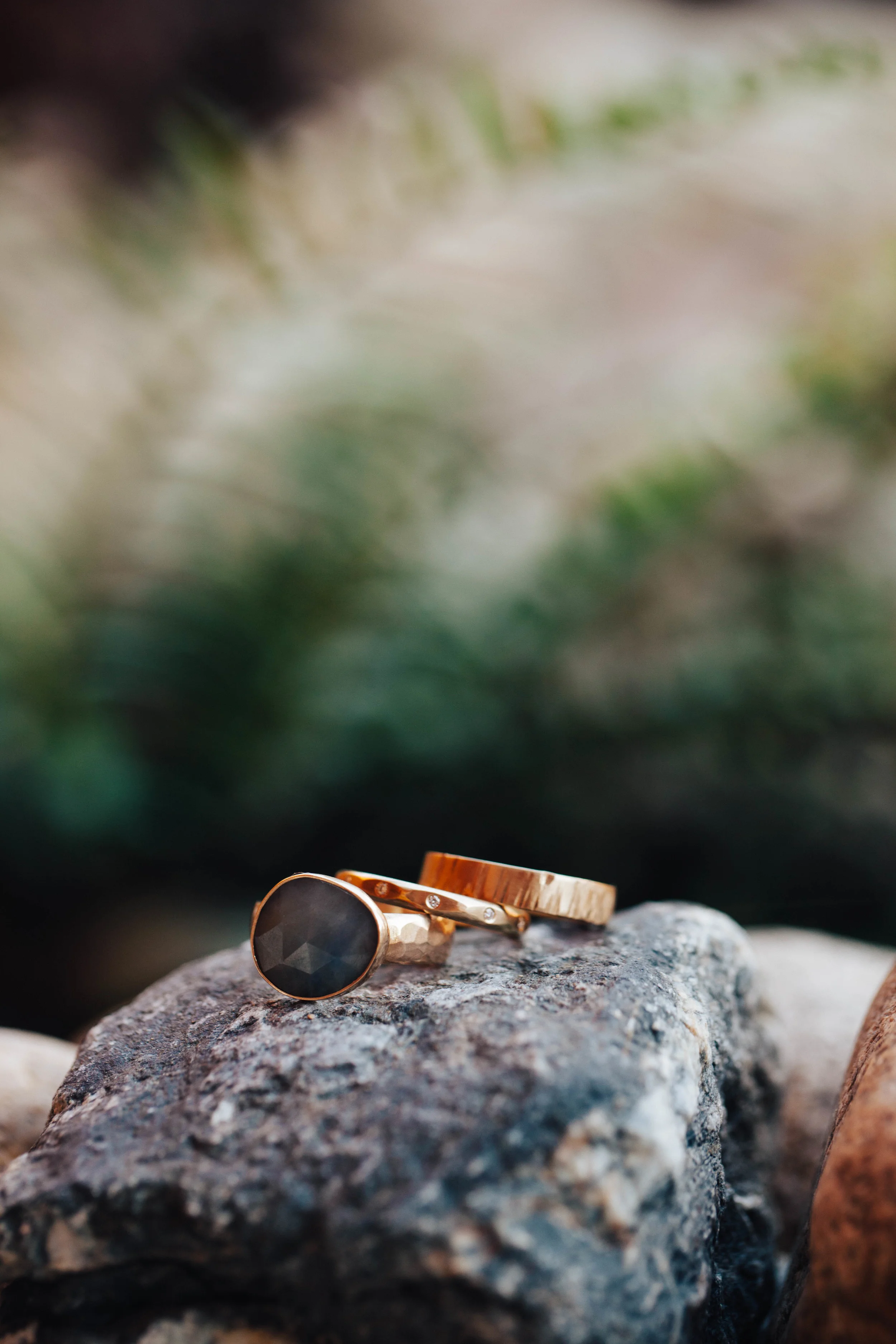 Rings by Leslie & Jared: 18k yellow gold; 4mm textured flat band, 2.5mm faceted half round band with flush set diamonds, and organic shap ed rose cut sapphire on a hammered band. Photo by Tim Kressin