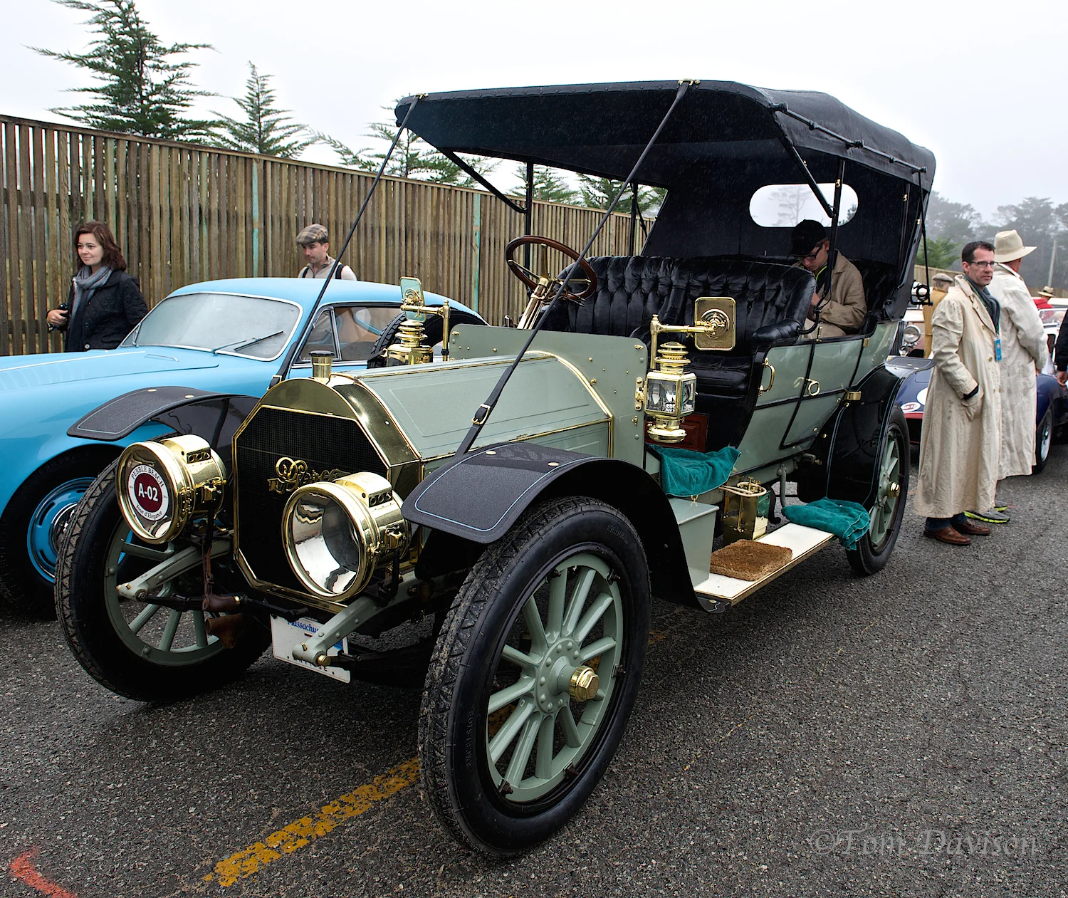 I am just guessing the gentleman sitting in the back is on a smart phone! Ah how times change. Notice the attention to taking care of not getting anything in the car . . . rags and little rug. Period dress?