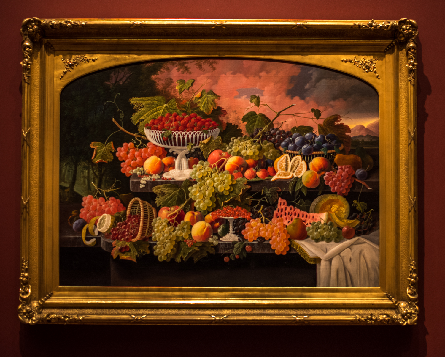 Two-Tiered Still Life with Fruit and Sunset Landscape 1867 , Severin Roesen (1815-1872), oil on canvas. From the information tag: "Severin Roesen's bountiful still life celebrates and reinforces the popular 19th century notion that America's natural resources distinguished the nation from the rest of the world. In majestic proportions and a vivid palette, an abundant variety of fruit sits atop a two-tiered marble shelf. The dense forest at left and the mountain landscape at right suggest the diversity and power of the American landscape. Painted around the time of the Civil War, the canvas' dramatic and somewhat threatening sky may suggest the question of whether or not America's unique democracy would prevail."