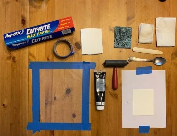 4. Here is my set up for printing each of these pieces. Clockwise from the wax paper: a) Wax Paper for my make-shift inking palette b) Blue Tape for my make-shift inking palette c) pieces of Stonehenge that I will print on d) the linocut block I wil…