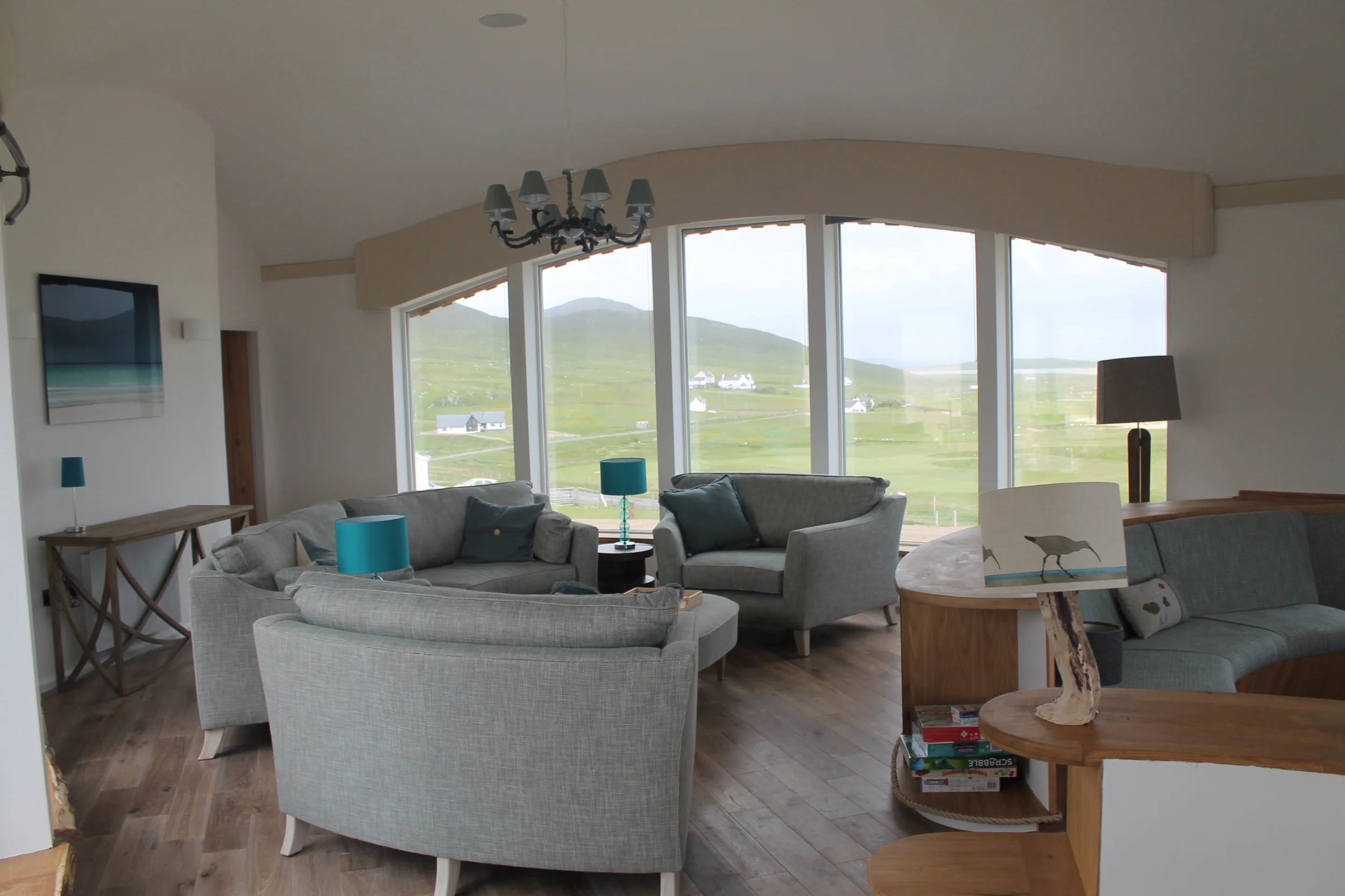 The bespoke sofas form a curve as a social space or a TV viewing area, with the Smart TV rising from the surface of the snug so that, when out of use, it does not interrupt views across the room. The large picture is "Before Rain" by Dudley Williams - we noticed that the weather outside reflects on the picture inside!